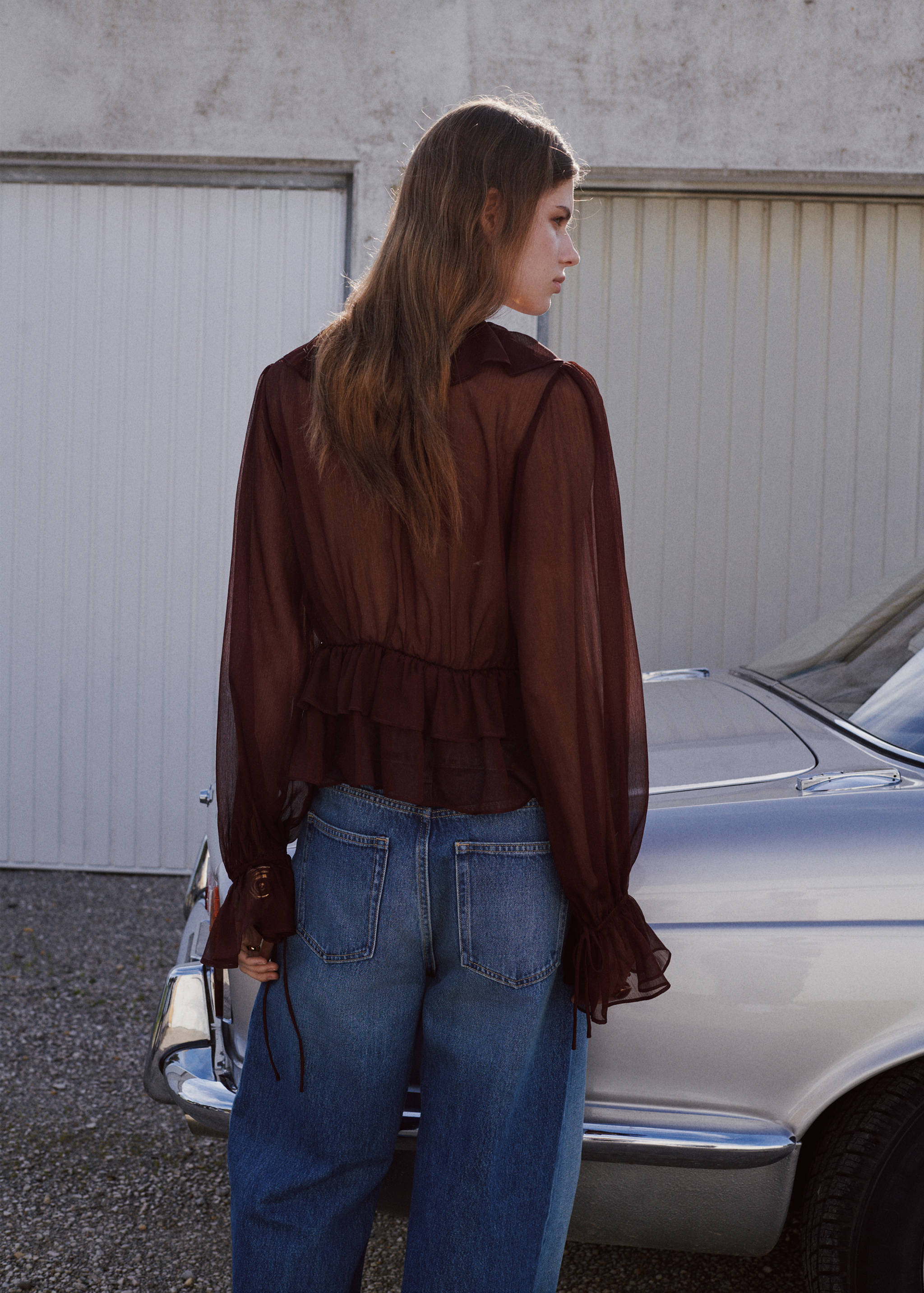 Dark burgundy sheer blouse with ruffled details and long sleeves, back view.