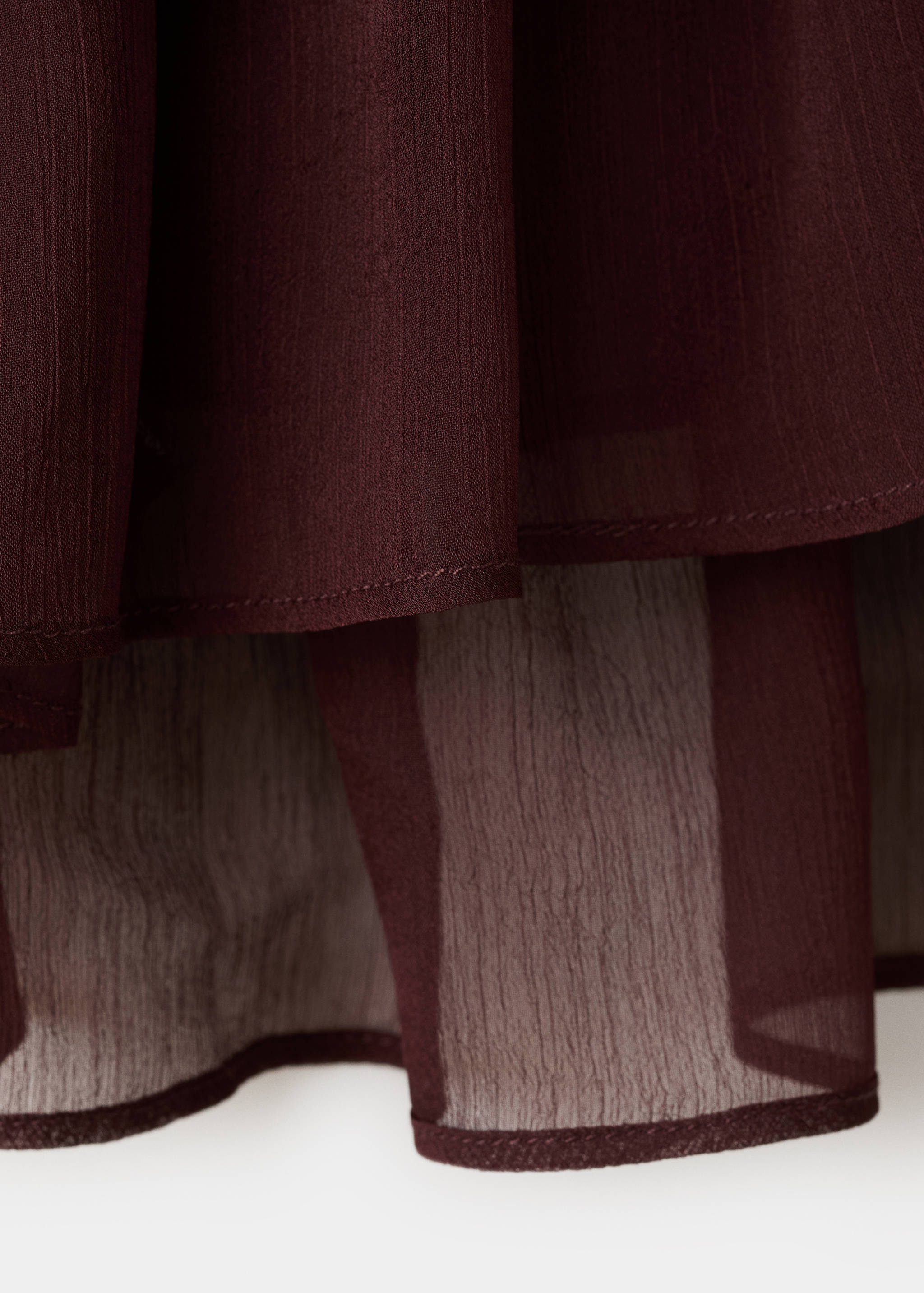 Close-up of dark burgundy blouse fabric showing sheer textured layers.