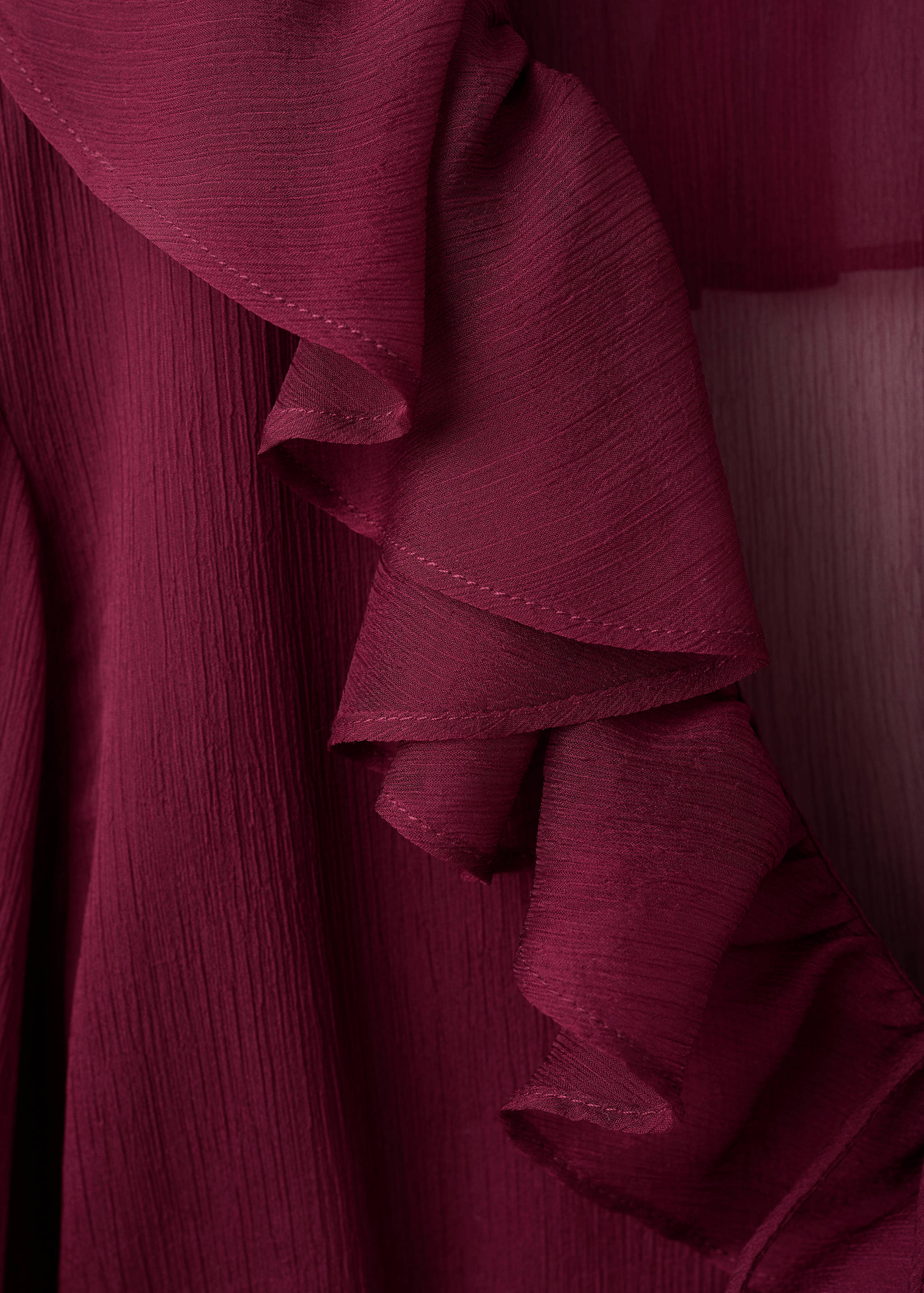 Close-up of burgundy blouse fabric with a crinkled texture and layered ruffles.