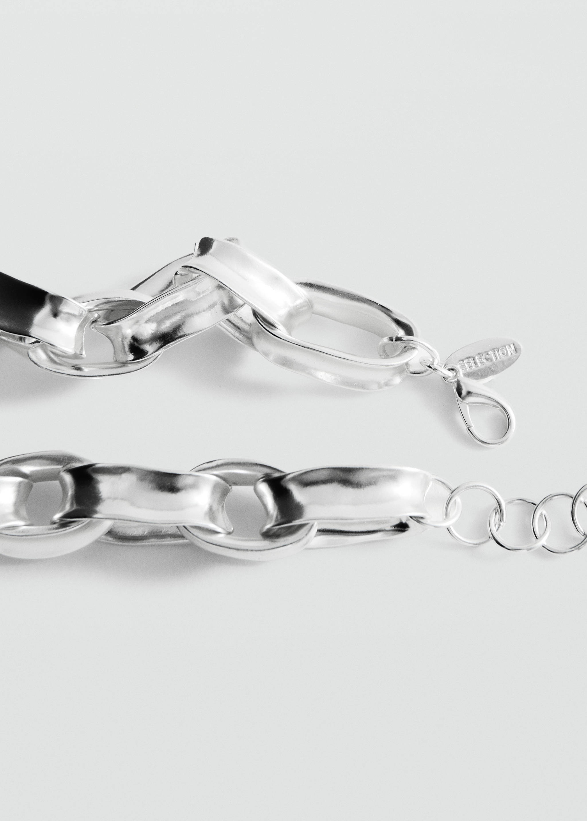 Close-up of a silver-coloured metal chain necklace with thick interlocking links and a branded tag.
