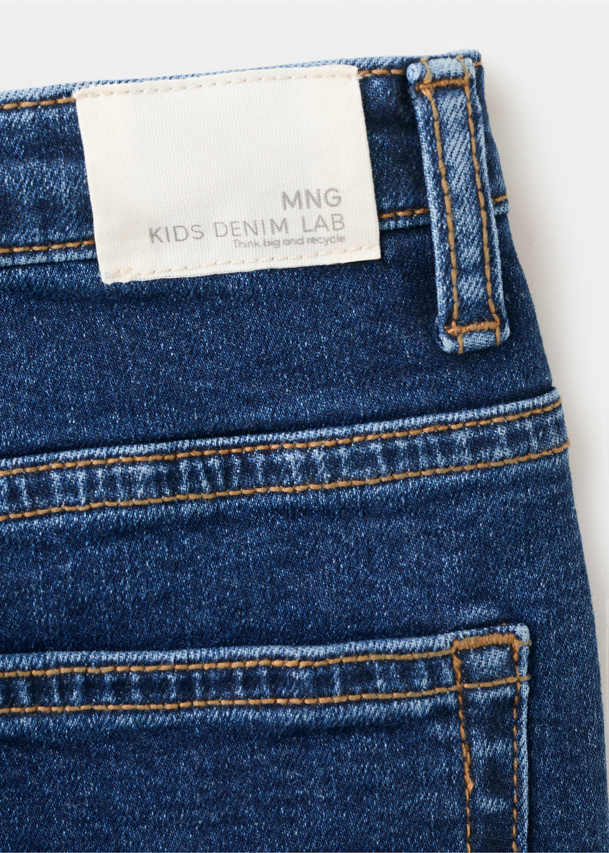 Close-up of blue denim trousers showing the waistband label and contrast stitching., Dark Blue. Ref: 27071259-00.