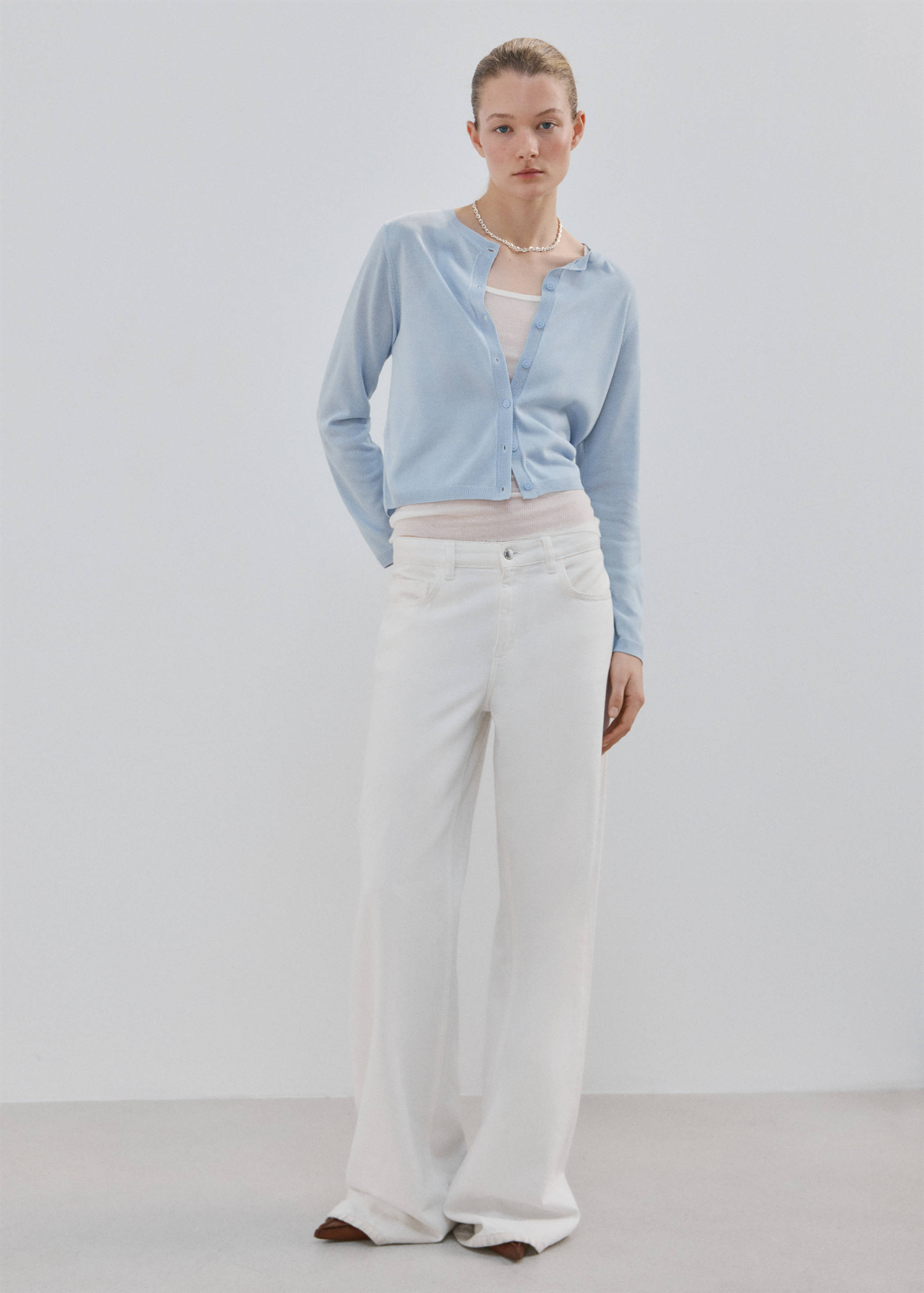 Light blue fine-knit cardigan worn with white trousers