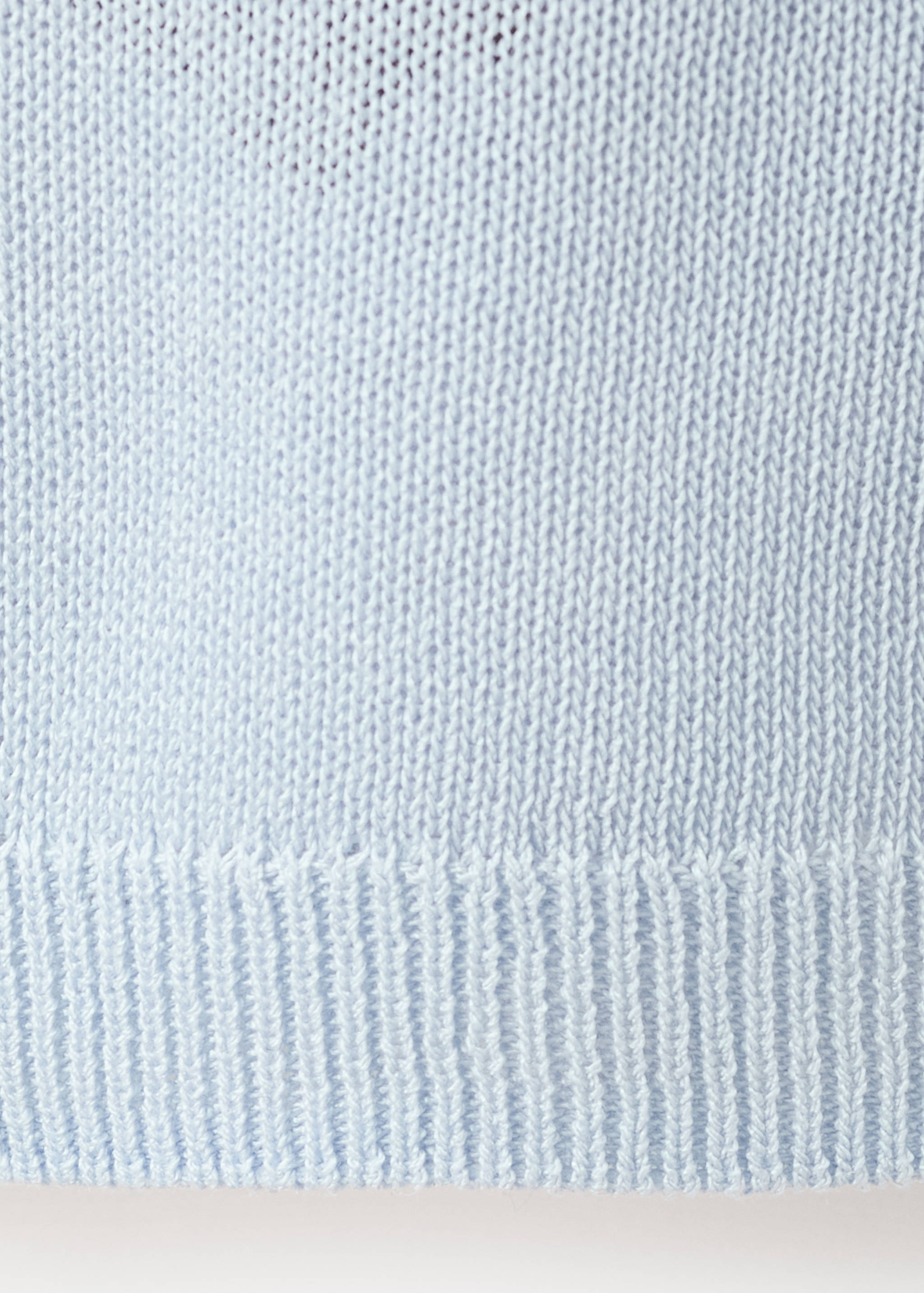 Close-up of a light blue knitted cardigan detail.