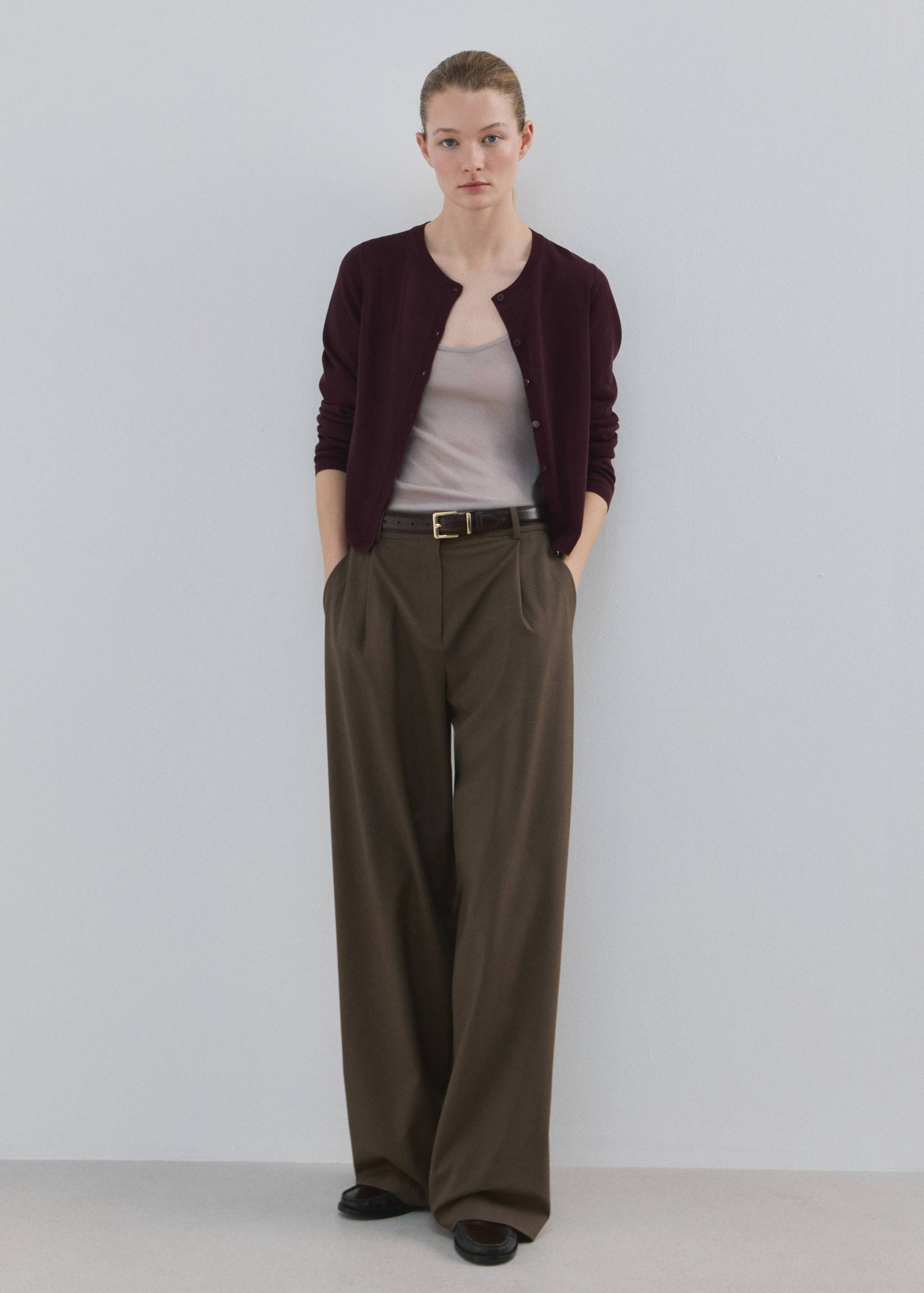 Dark burgundy round-neck cardigan styled with a light top and wide-leg trousers.