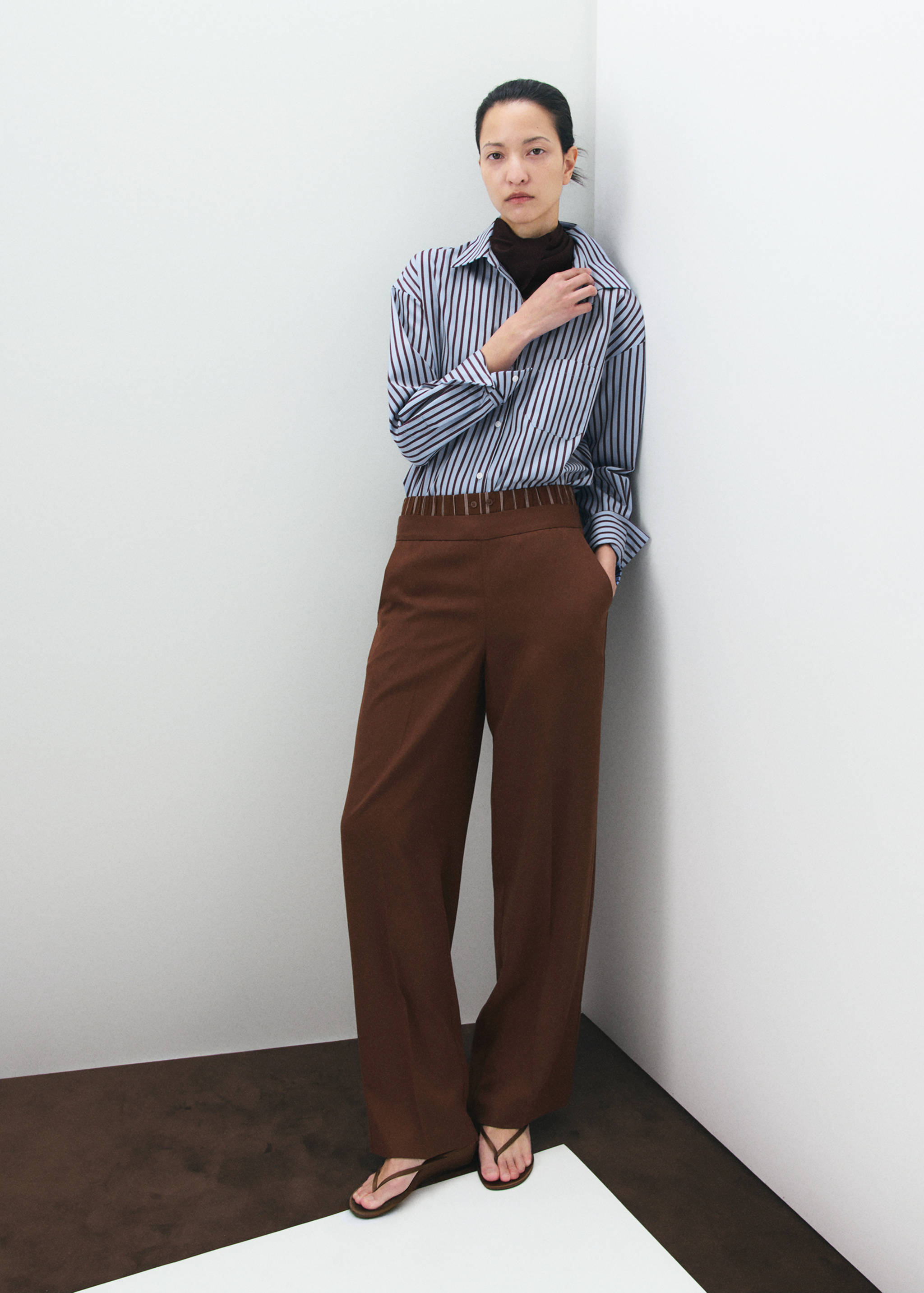 Striped long-sleeve shirt with a pointed collar and chest pocket worn with brown trousers.