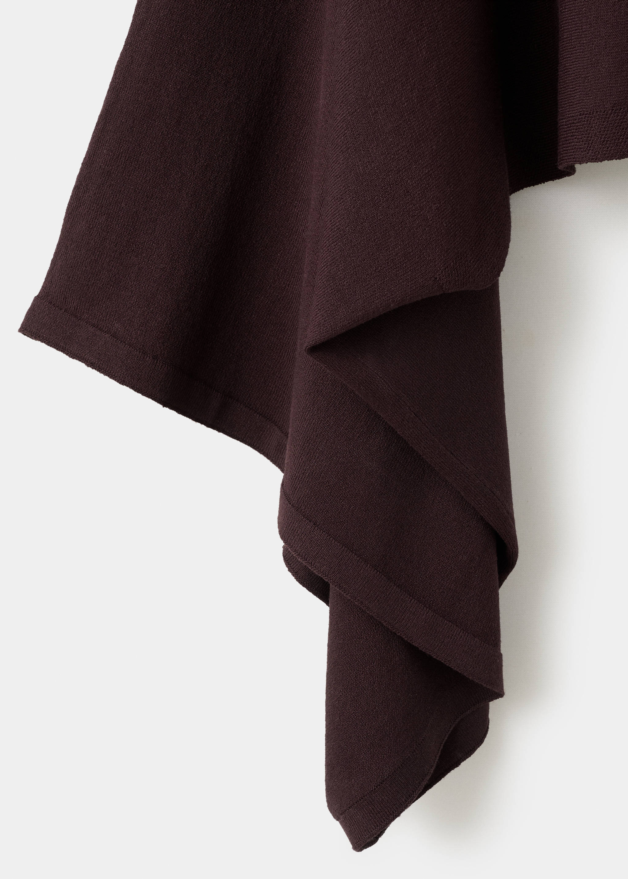 Dark brown knitted cape fabric detail showing texture and drape.