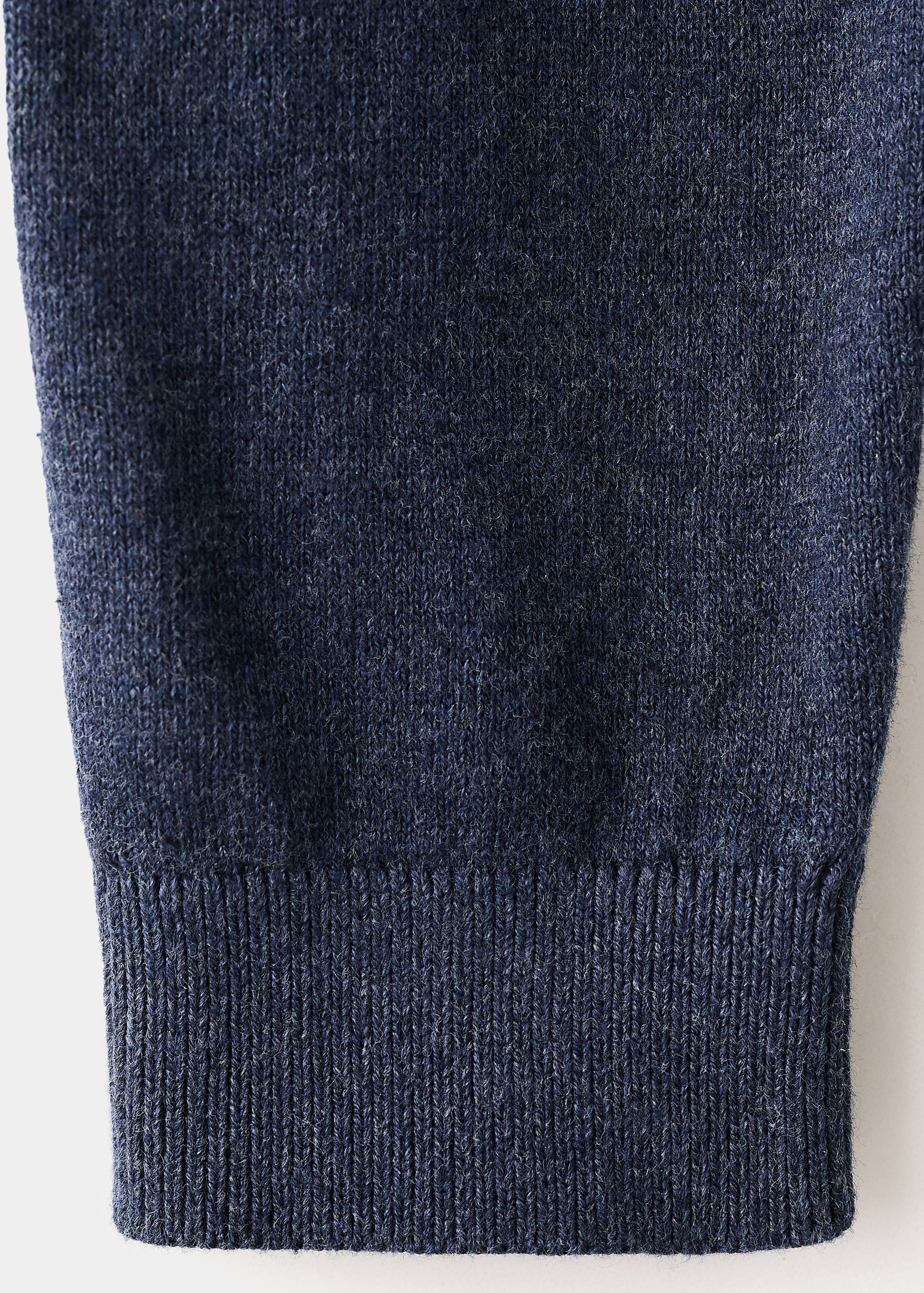 Close-up of the knitted fabric and ribbed hem of a dark navy blue cardigan.