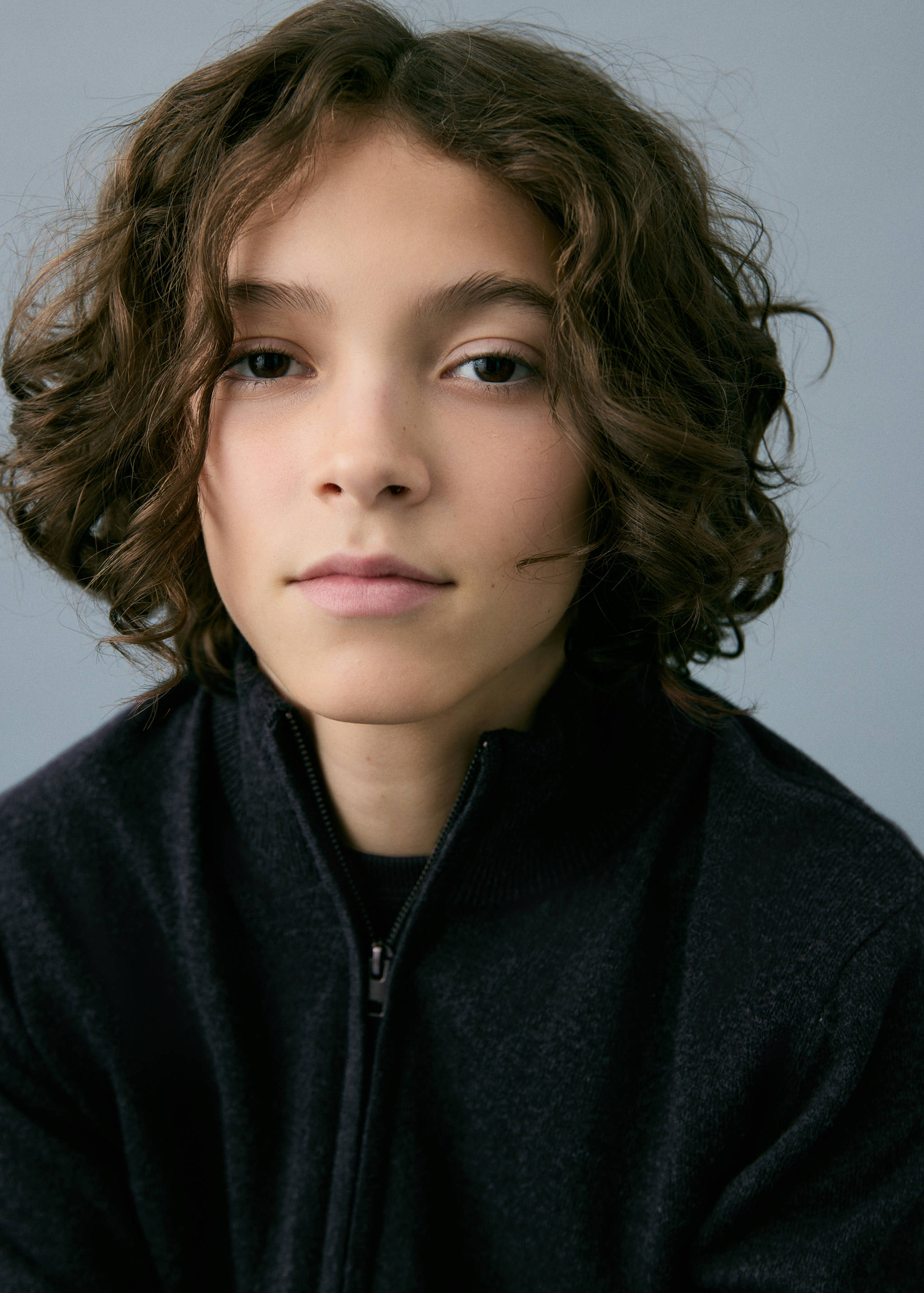 Close-up of a child wearing a dark grey zip-up knitted cardigan.