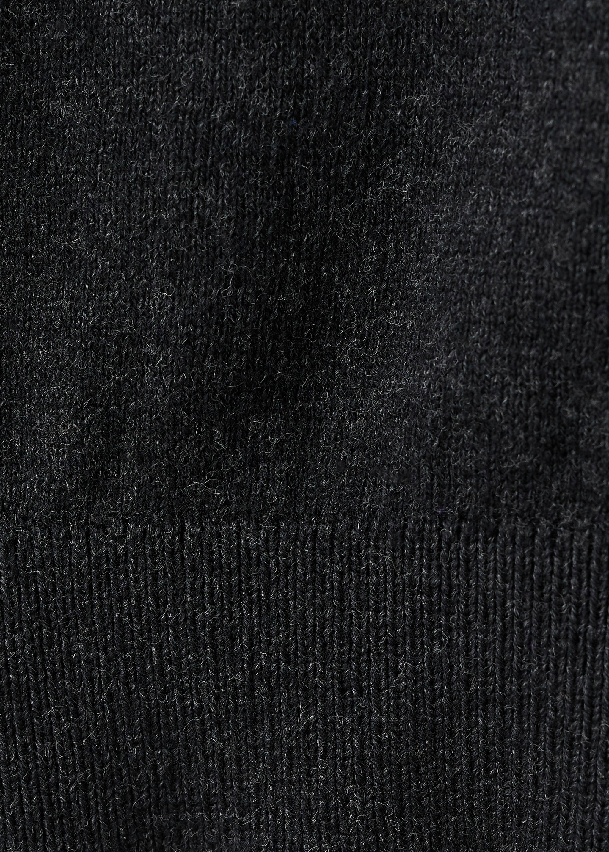 Close-up of the fine-knit and ribbed fabric texture of a dark grey cardigan.