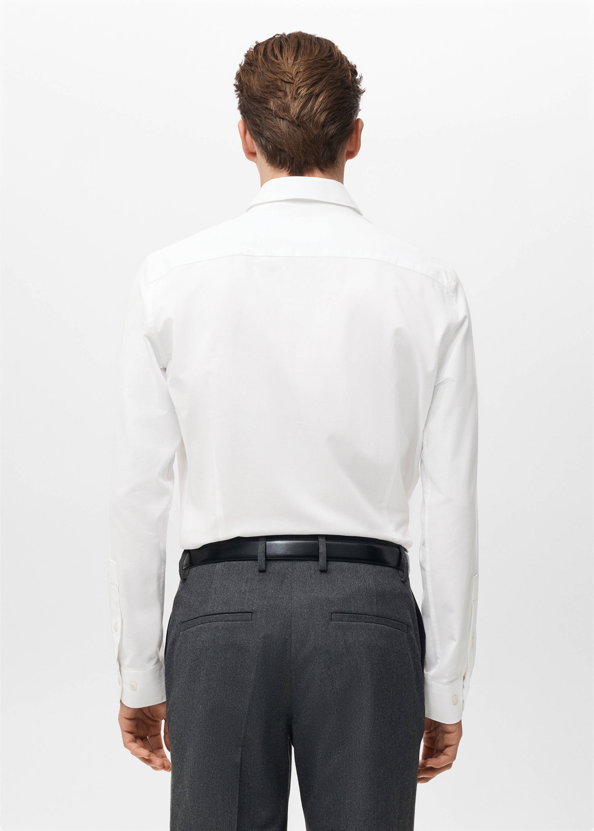 Back view of a white long-sleeved shirt tucked into dark trousers.