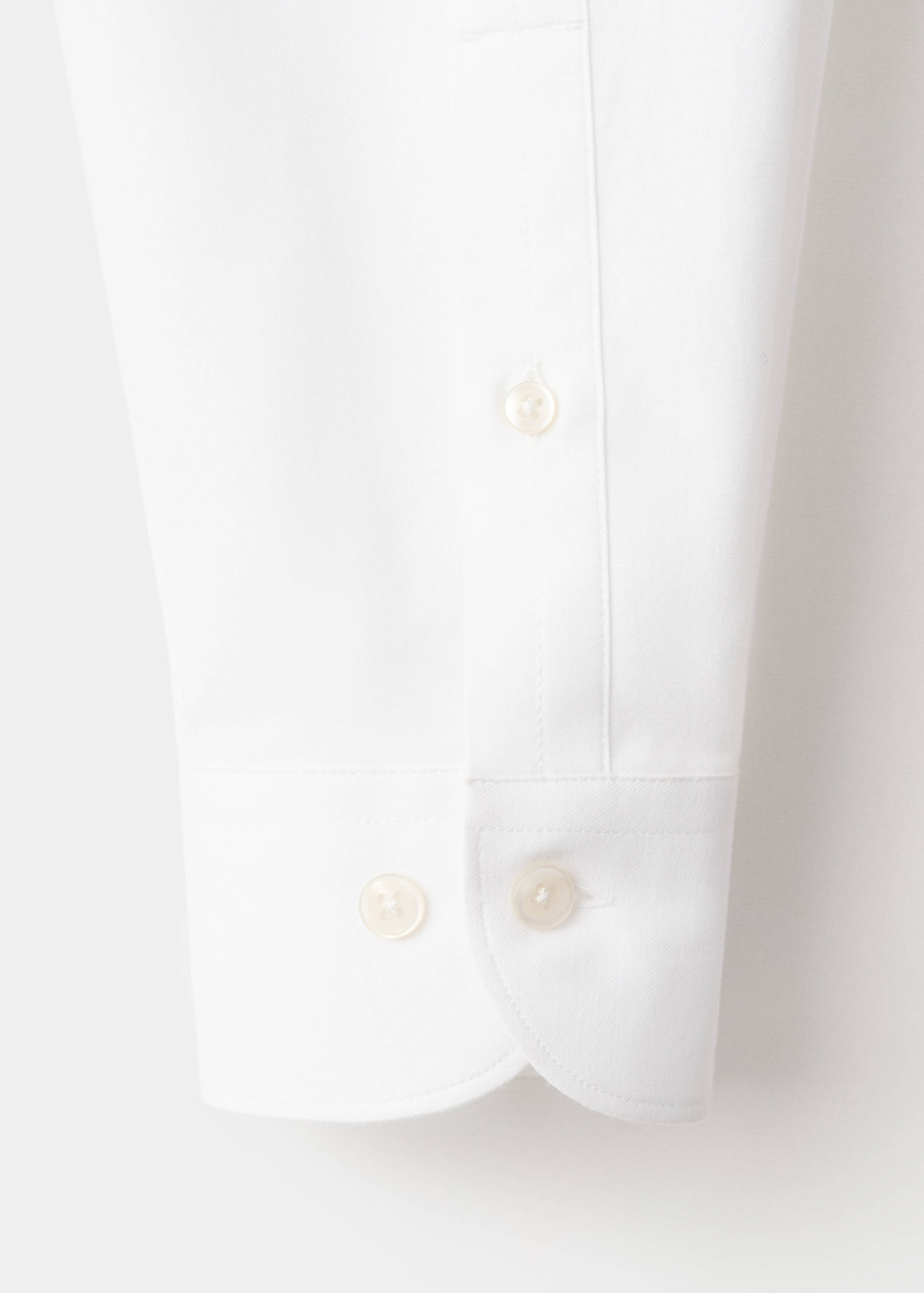 Close-up of white shirt fabric and buttoned cuff detail.