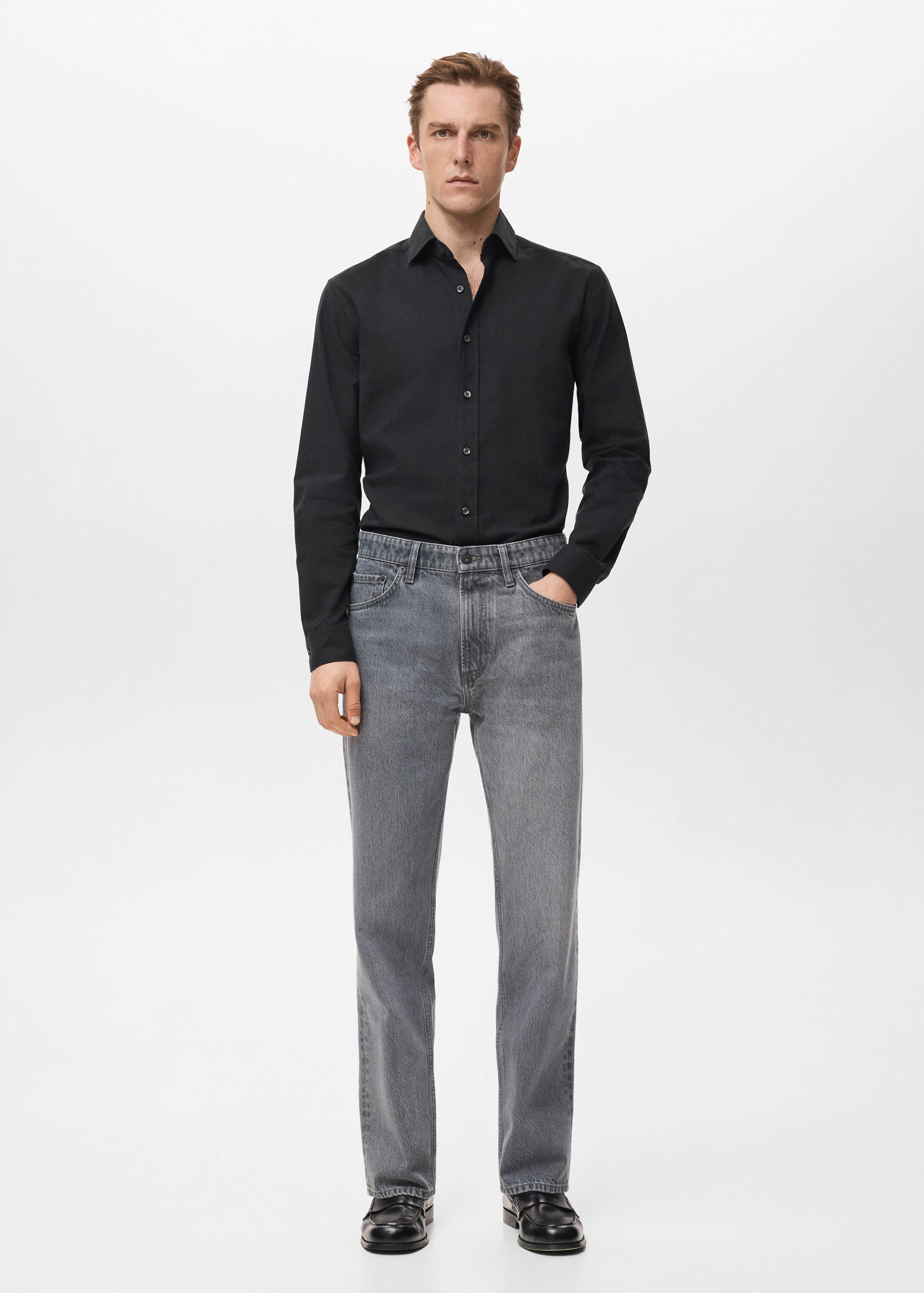 Black long-sleeved shirt with classic collar and button fastening, worn with grey trousers.