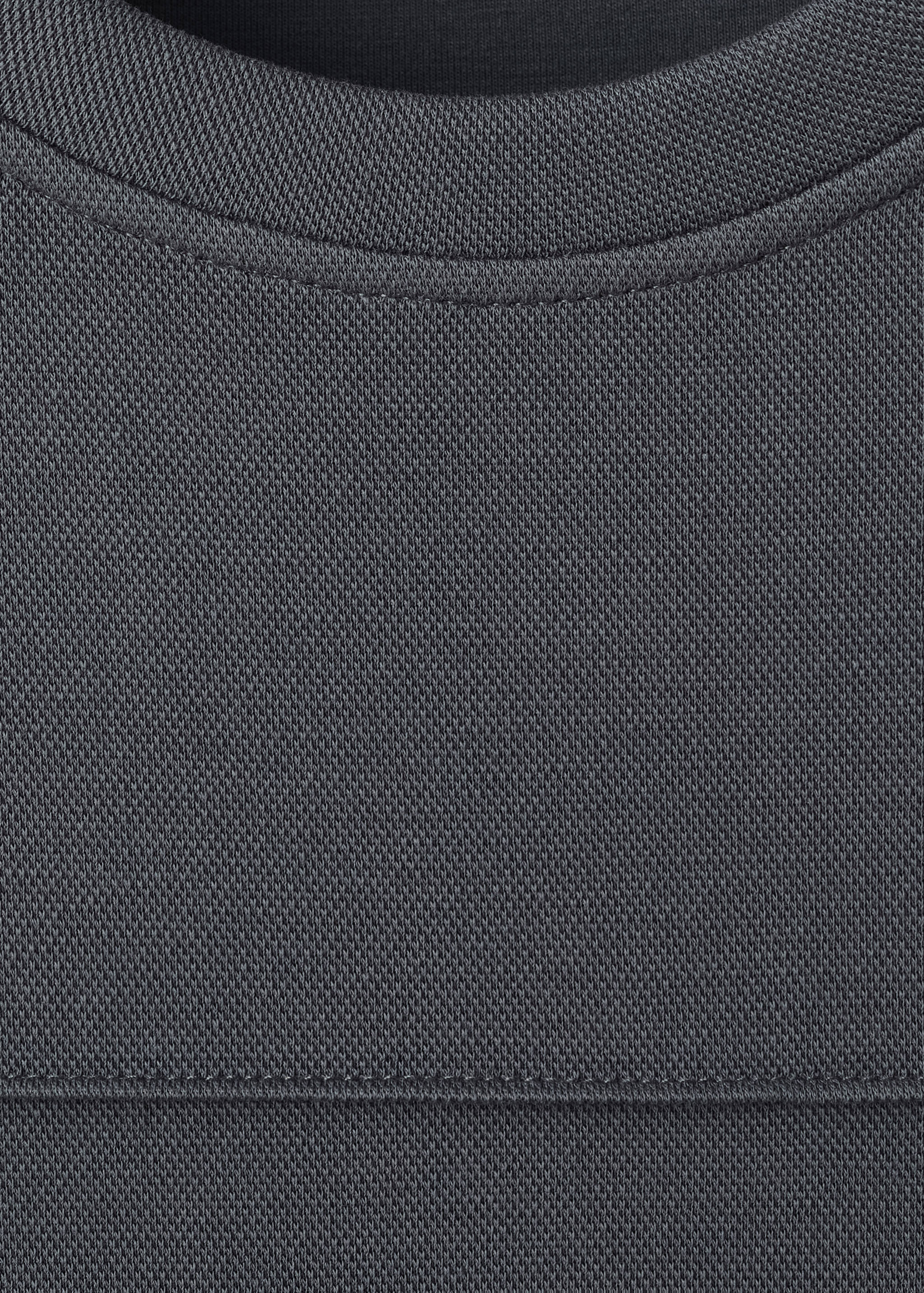 Dark grey sweatshirt detail focusing on the ribbed crew neckline.