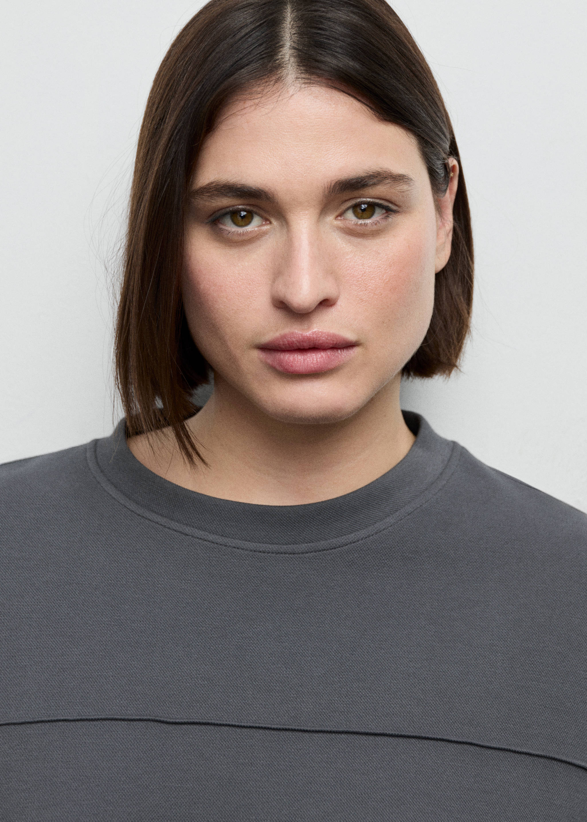 Dark grey sweatshirt with a crew neck and chest seam, in a close-up portrait.