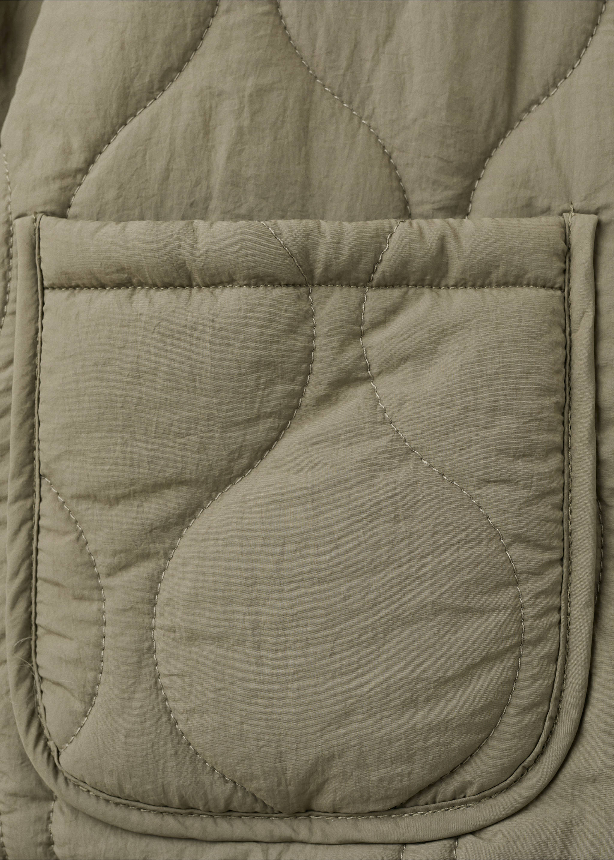 Close-up of olive green quilted parka fabric with curved stitching and a patch pocket., Khaki. Ref: 27084432-00.