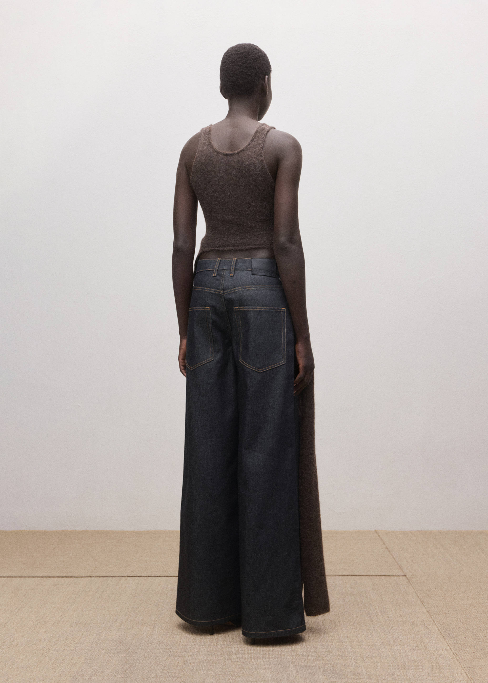 Dark denim trousers with wide legs, shown from the back.