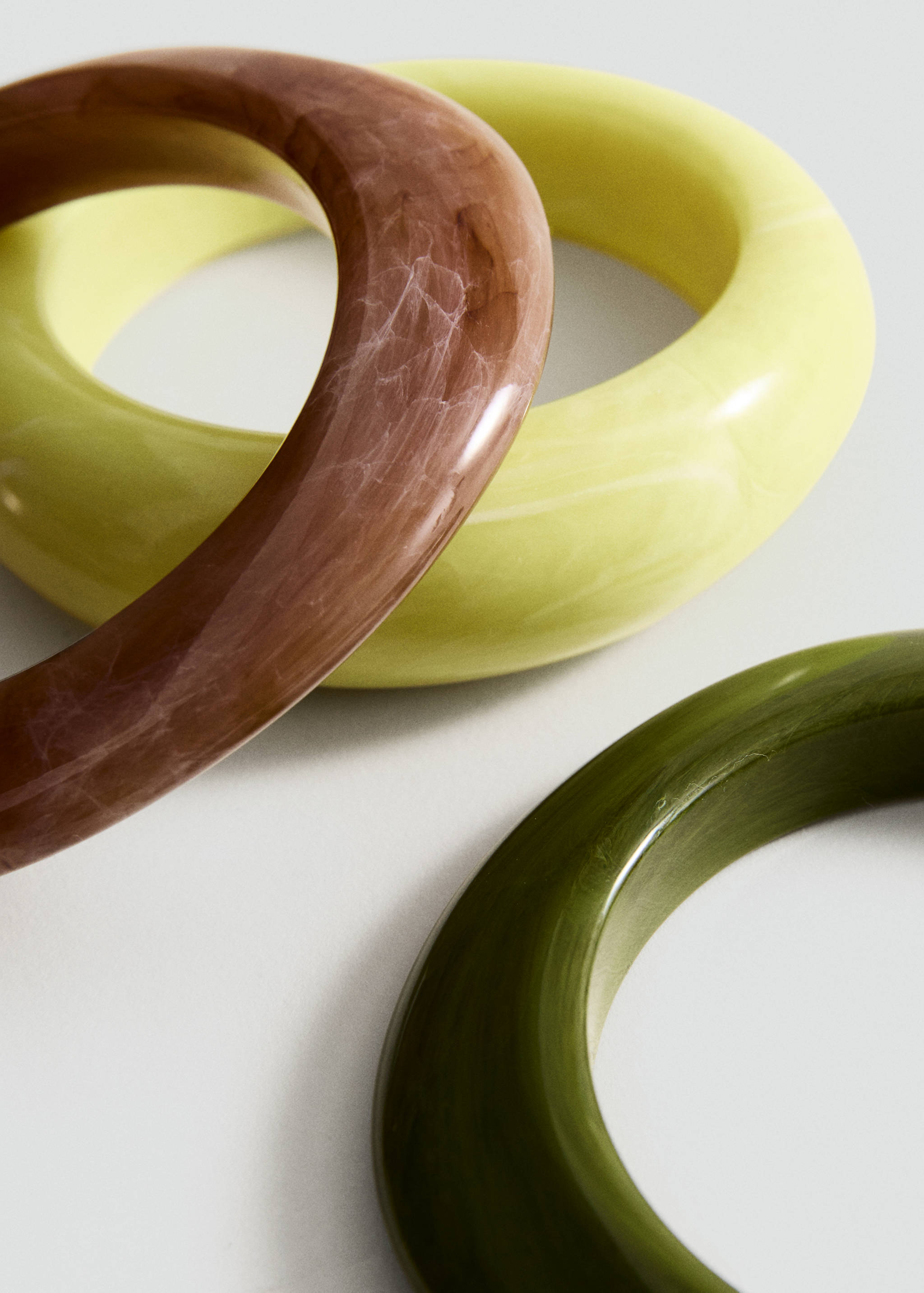 Three chunky resin bangles in marbled brown, pale yellow, and olive green.