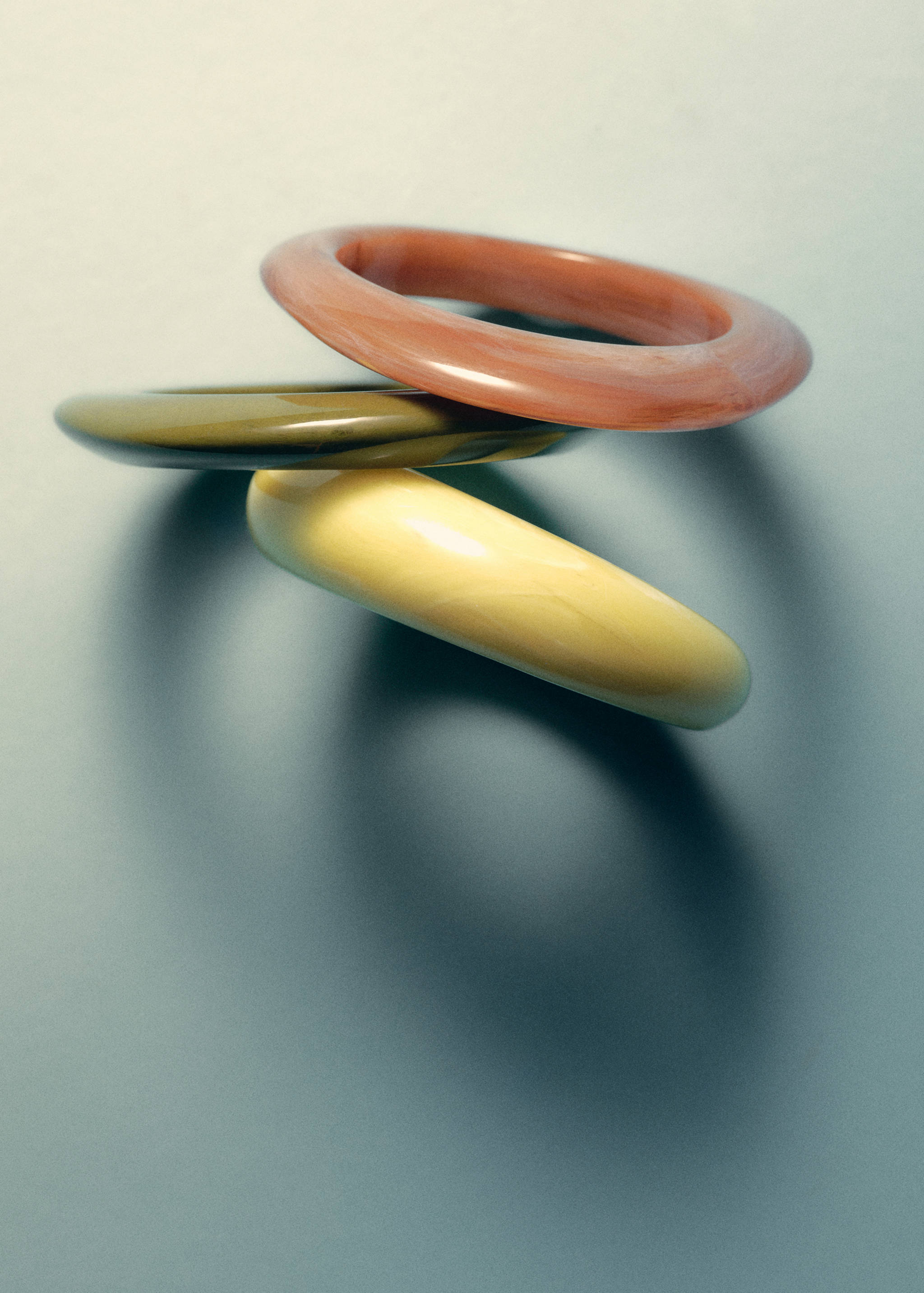 Set of three chunky resin bangles in pink, olive green, and pale yellow.