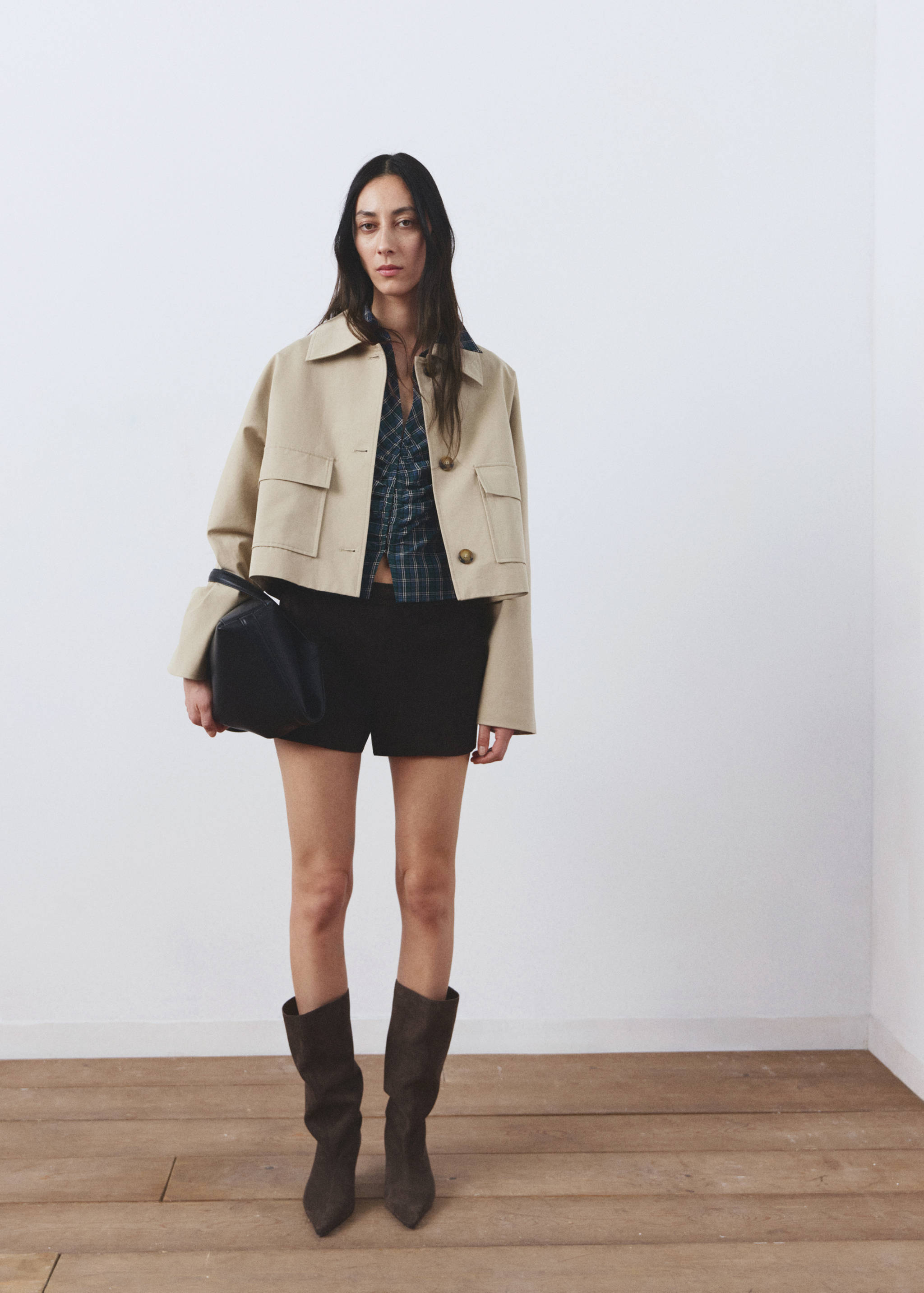Navy blue and green plaid blouse worn with a cropped beige jacket and black shorts.