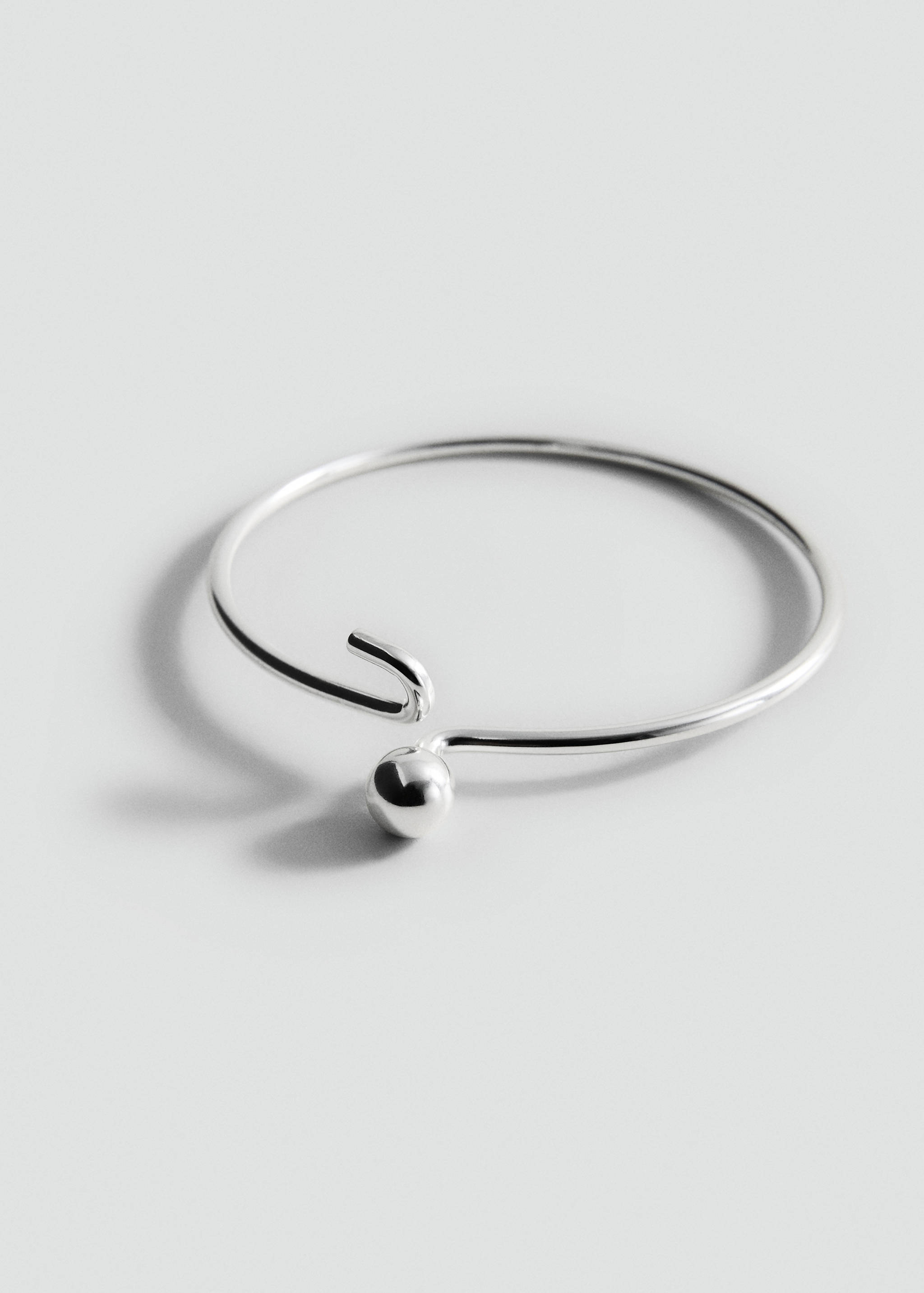 Silver-toned metal bangle bracelet with a spherical ball detail.