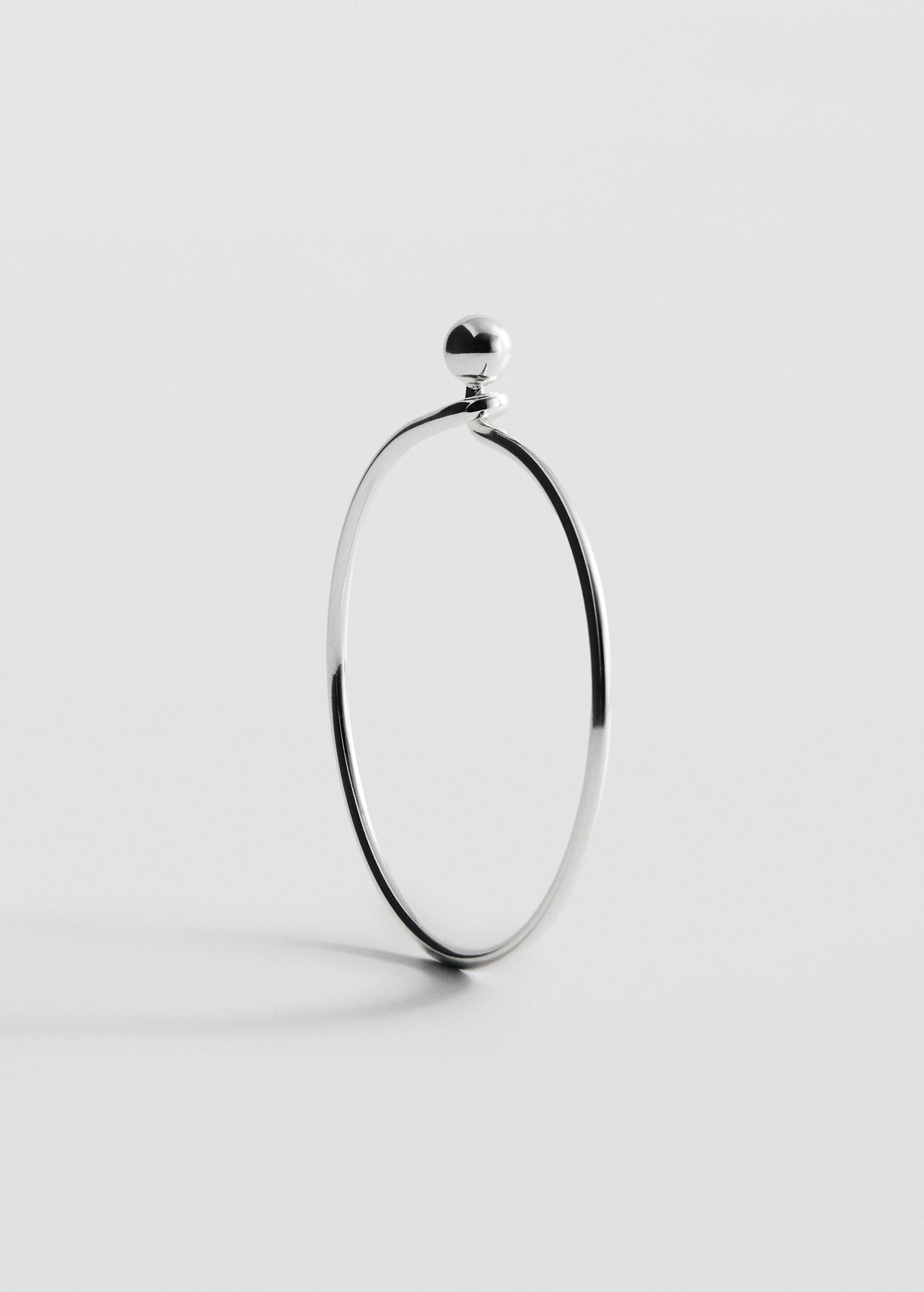 Silver-toned metal bangle bracelet with a spherical bead closure detail.