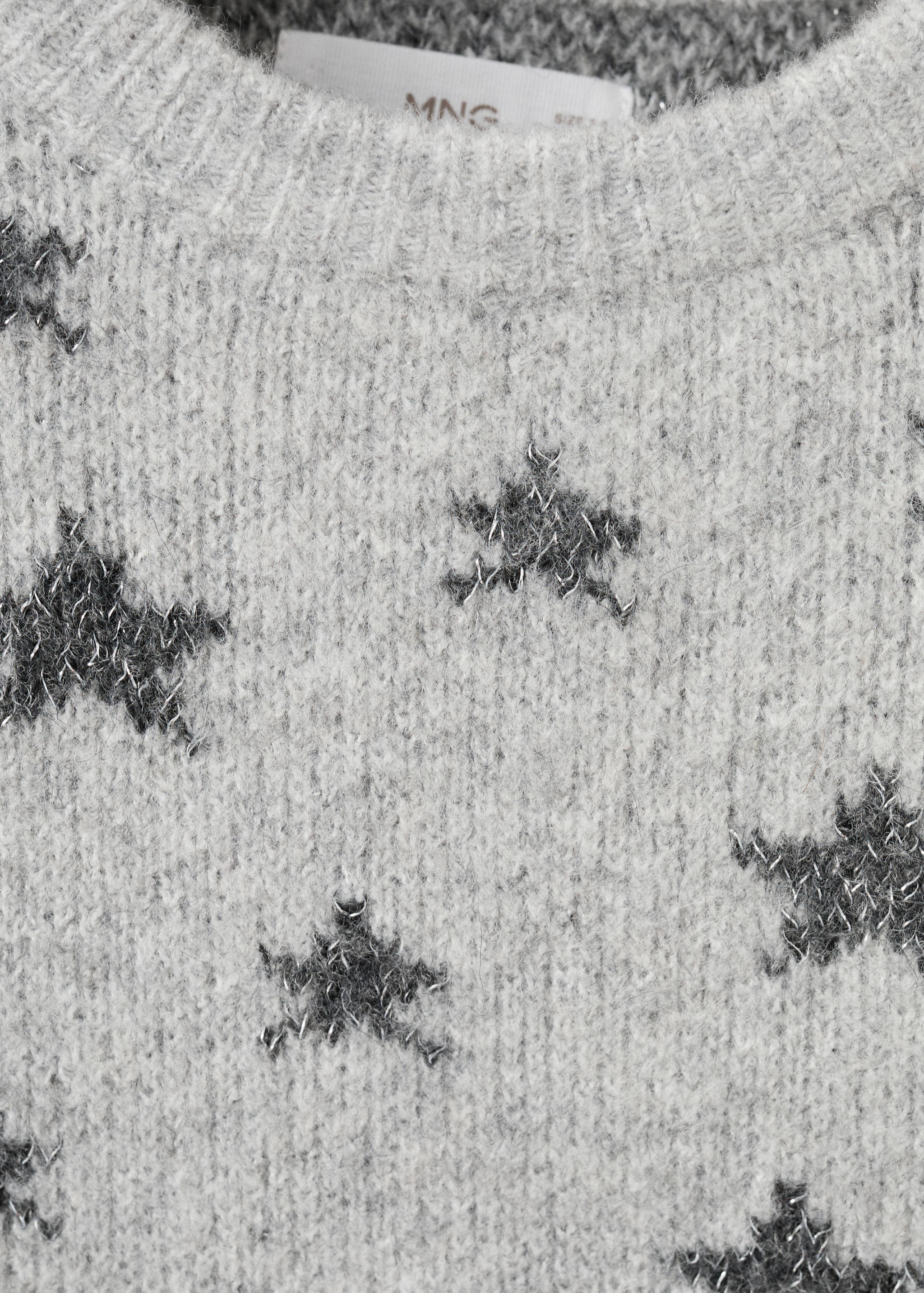 Close-up of a grey knit jersey with dark grey star motifs and a crew neck.
