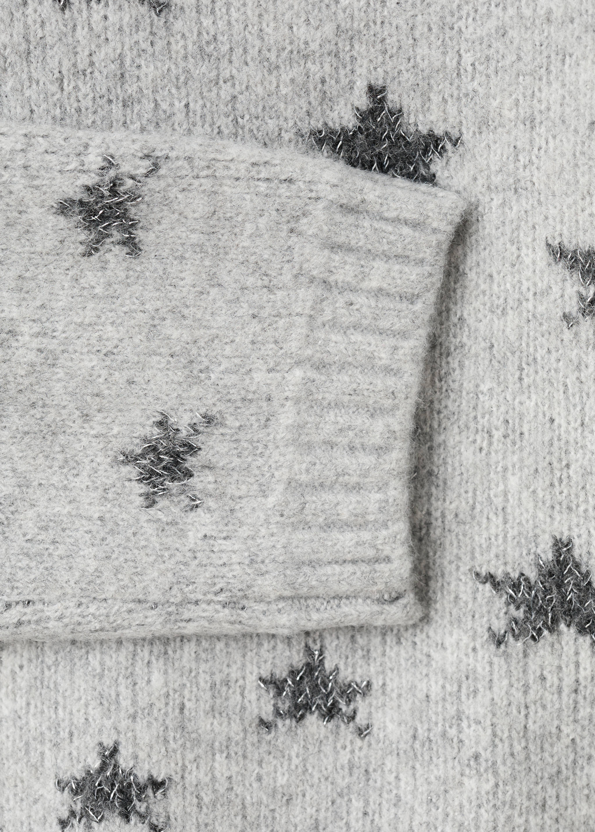 Close-up of a grey knitted jumper with a dark grey metallic star pattern.