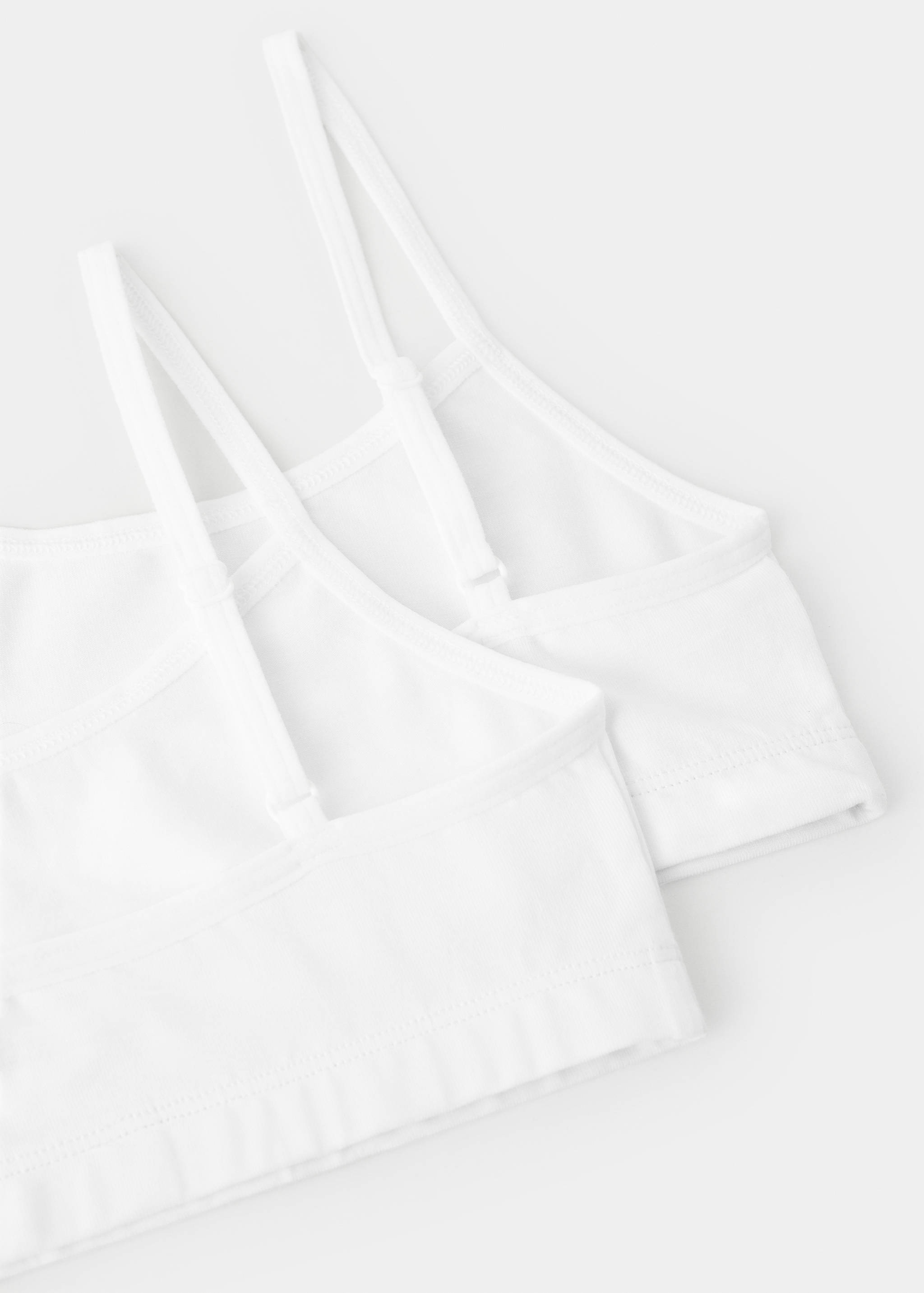 Close-up fabric detail of a pack of two white bras with double straps.