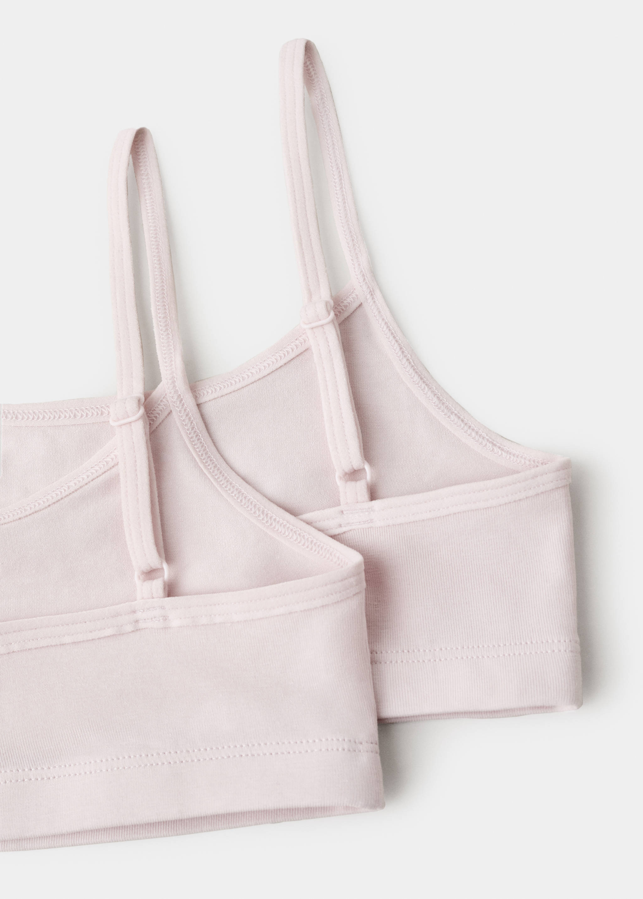 Close-up of a light pink bralette showing adjustable straps and smooth fabric.