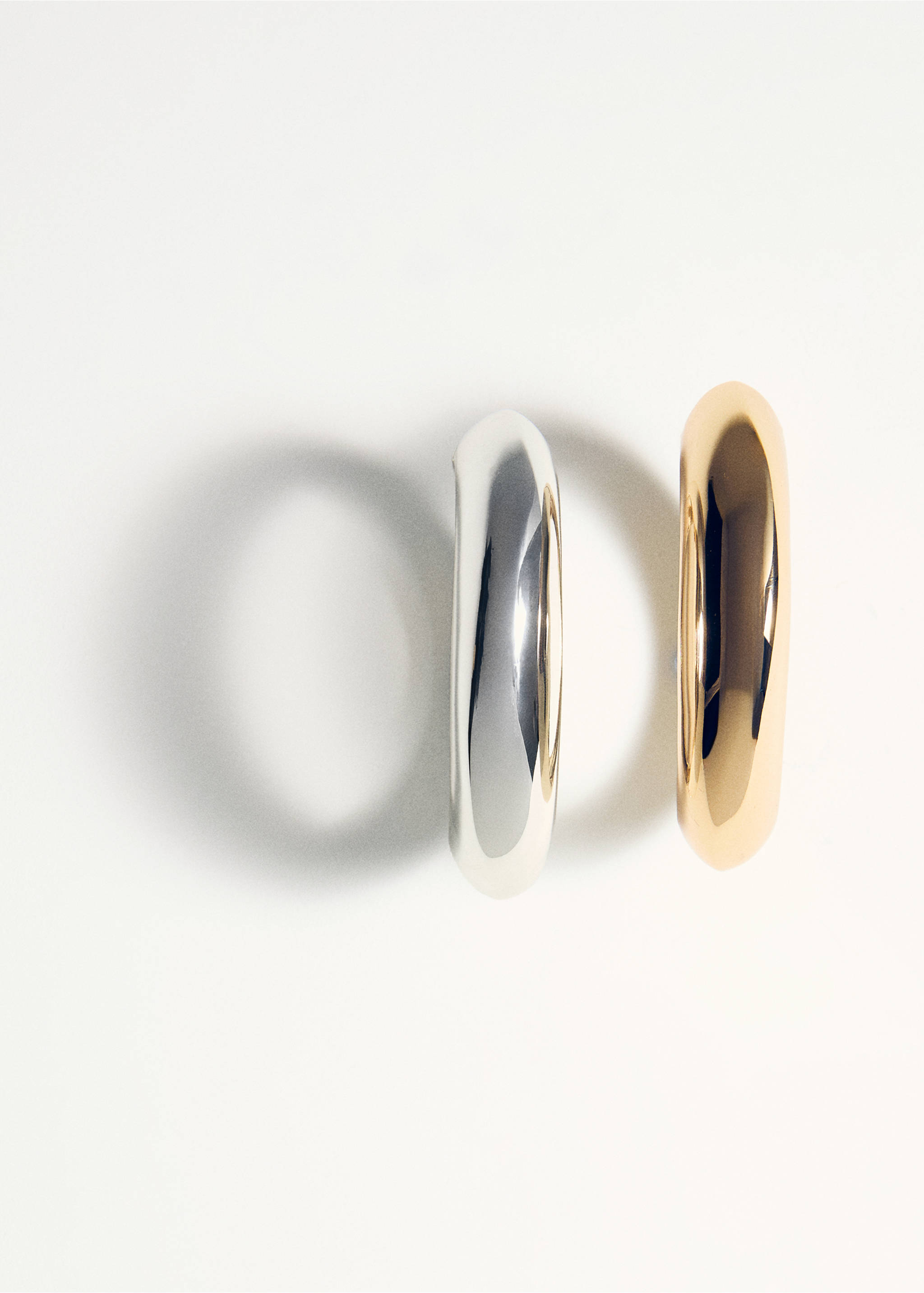 Two thick, polished metal bangles in silver and gold tones., Gold. Ref: 27091287-00.
