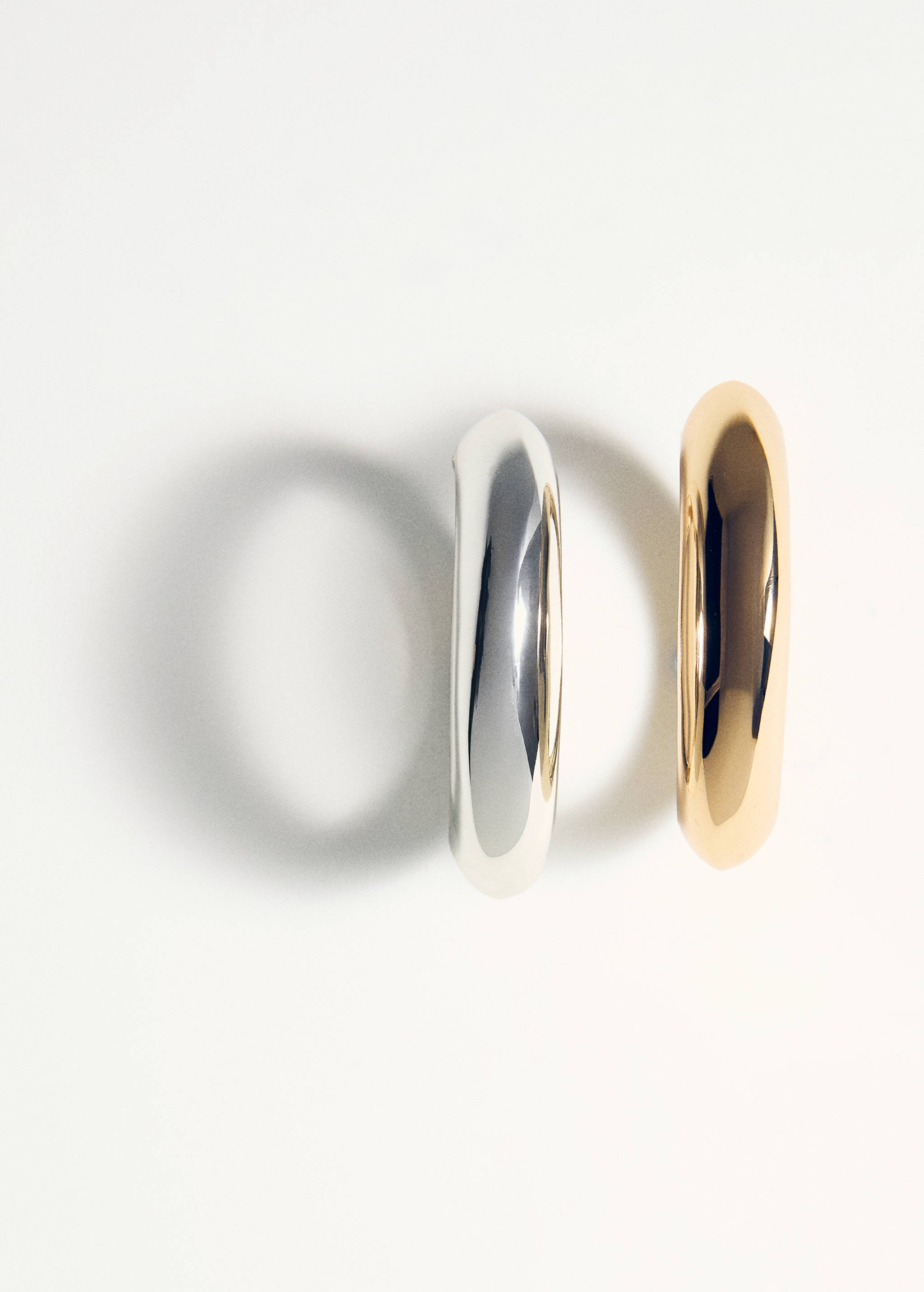 Two thick, polished metal bangles in silver and gold tones.
