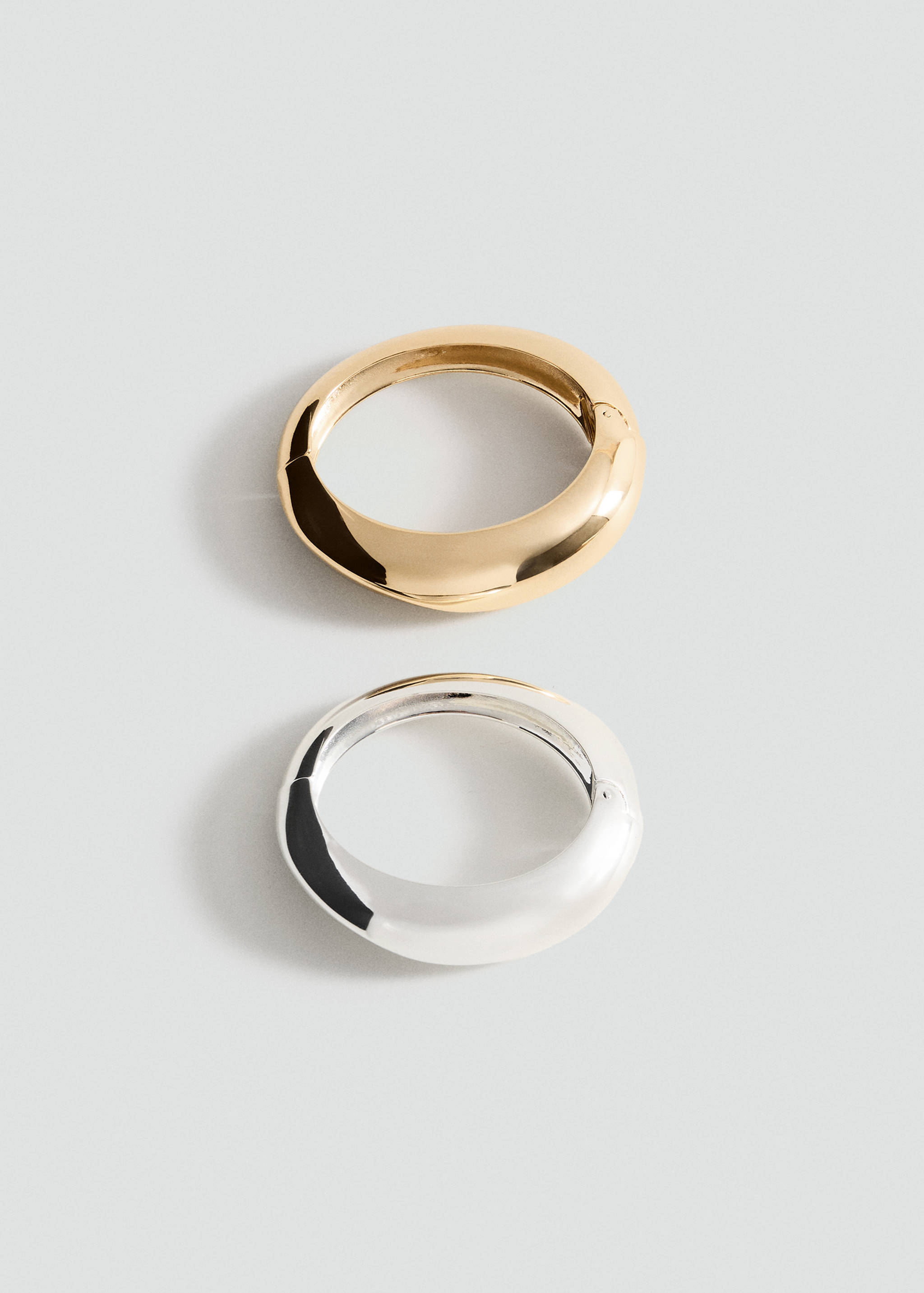 Set of two chunky polished metal bracelets in gold and silver.