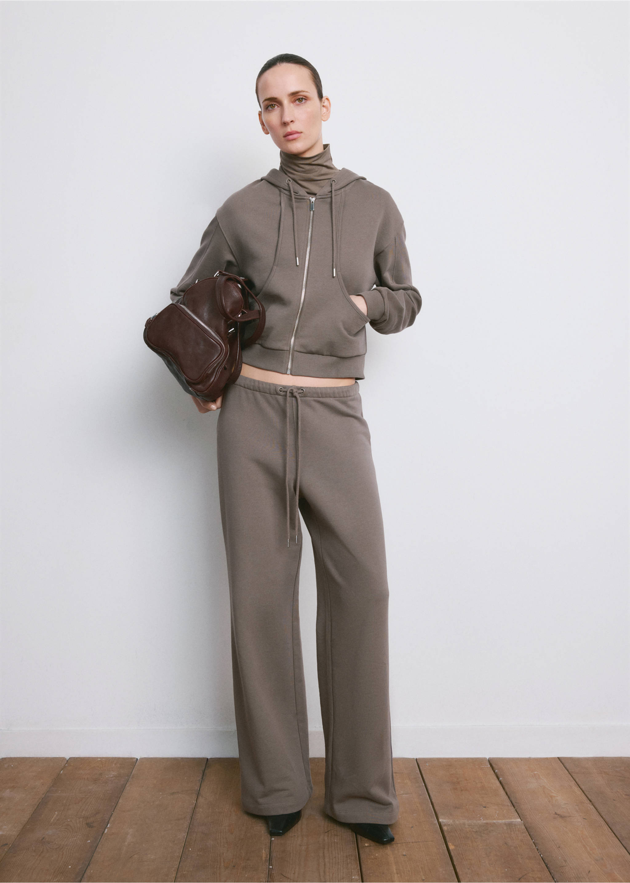Grey-brown cropped zip hoodie with drawstring, worn with matching trousers and a dark brown bag., Grey. Ref: 27093730-00.