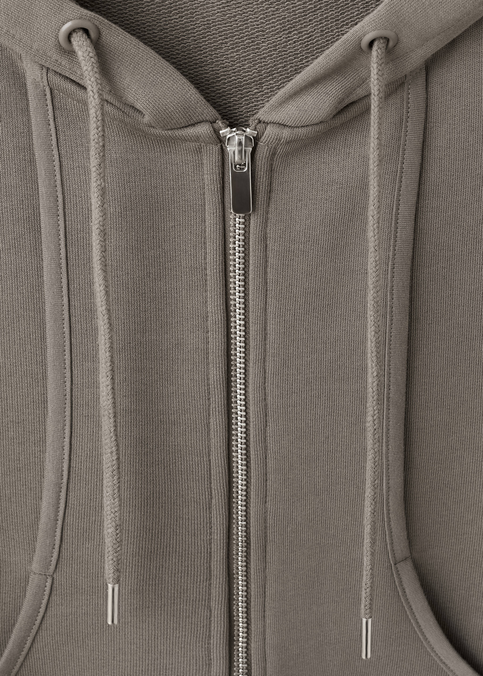 Taupe-grey zip-up sweatshirt detail featuring a hood, metal zip, and drawstrings.