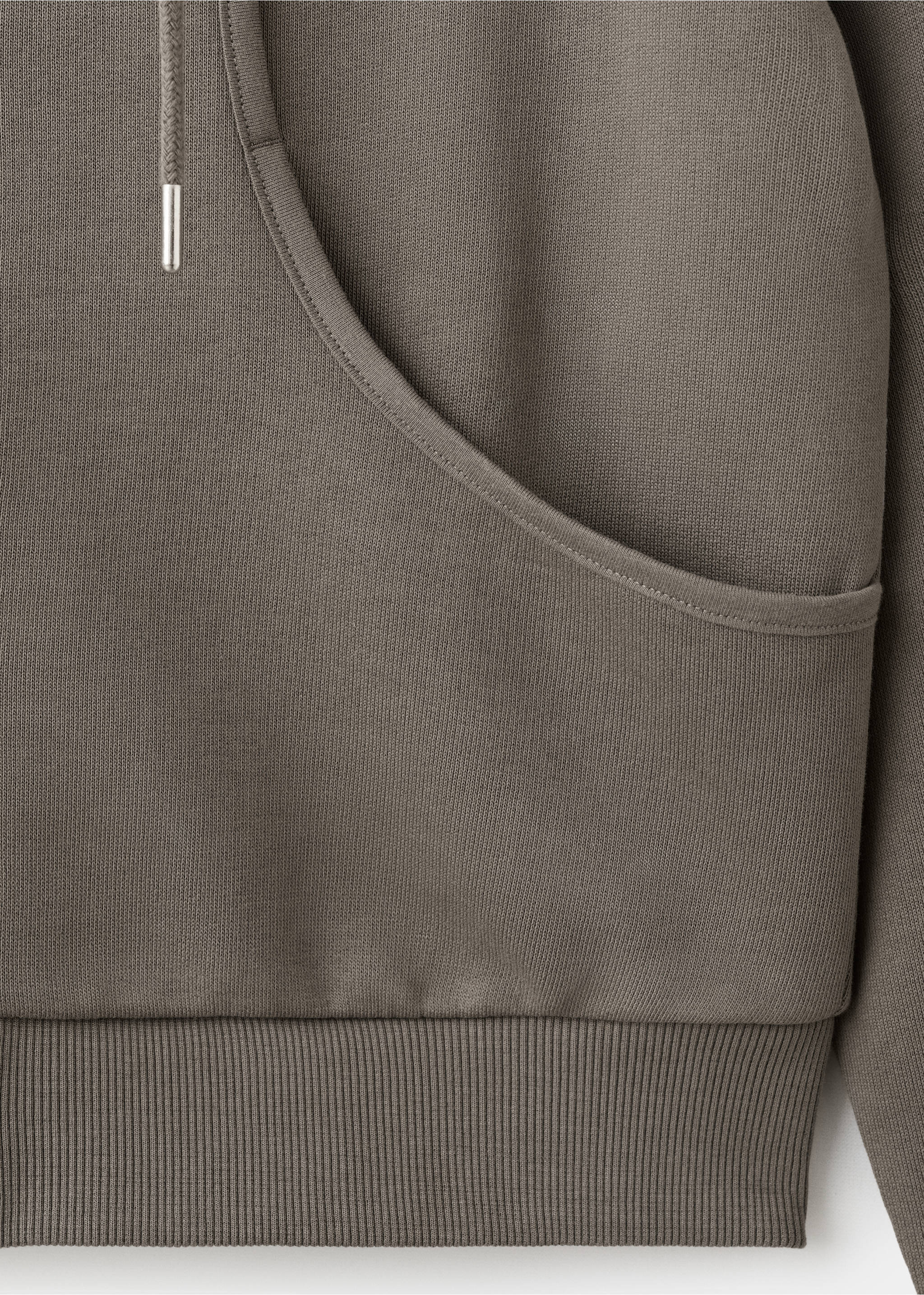 Close-up of fabric and kangaroo pocket detail on a greyish-brown hoodie., Grey. Ref: 27093730-00.