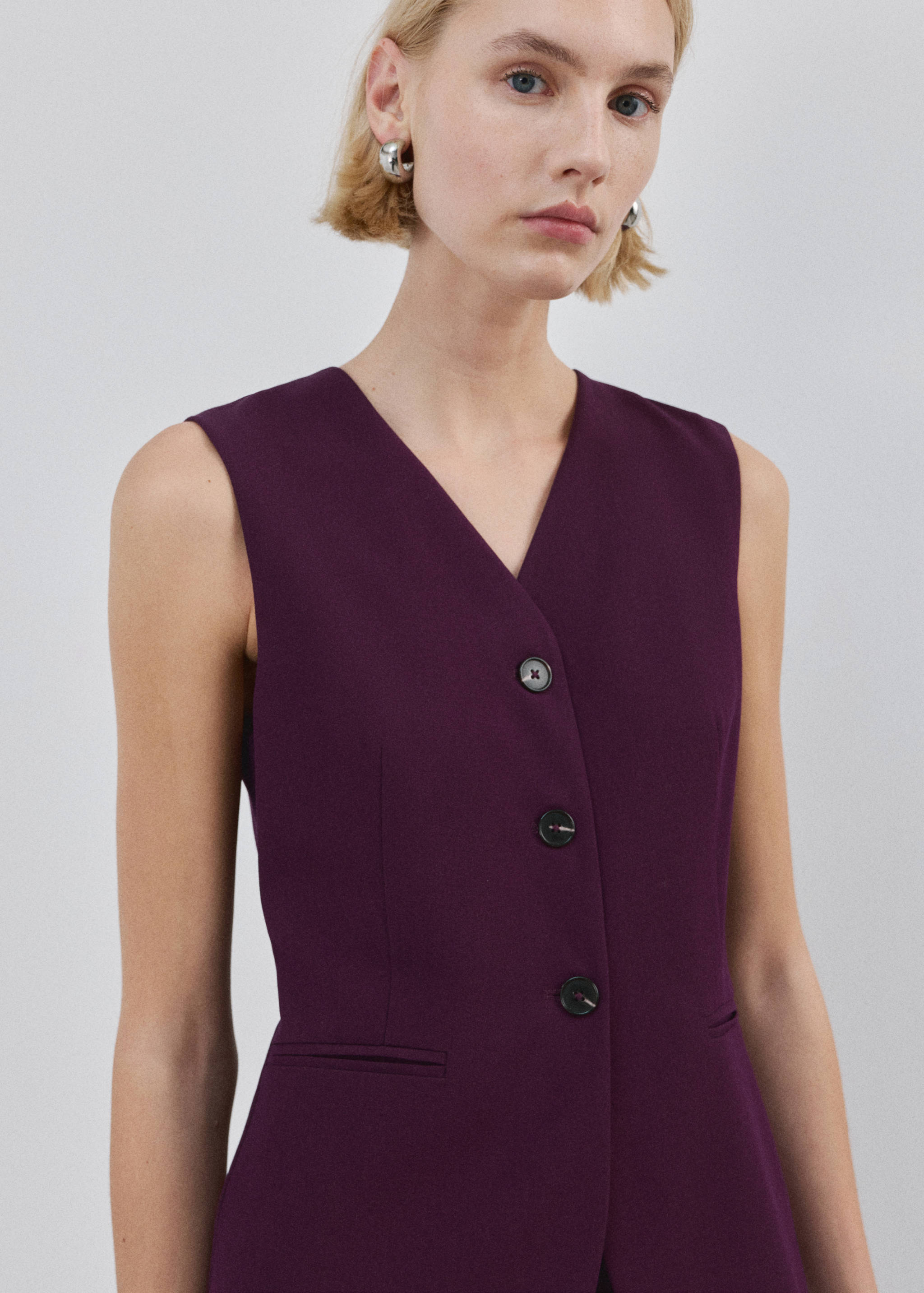 Dark purple V-neck sleeveless jumpsuit with front buttons.
