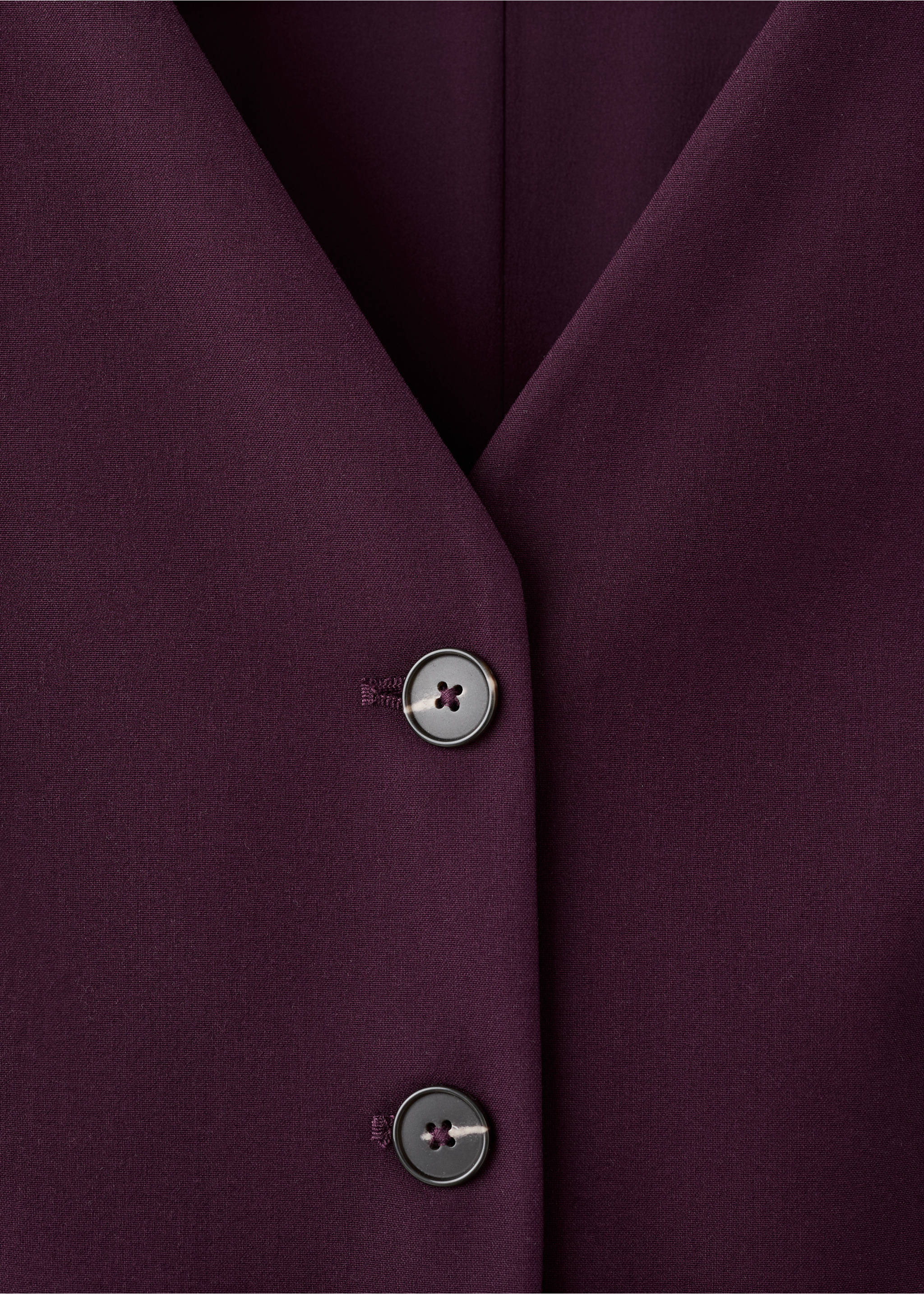 Close-up of a dark purple jumpsuit V-neck and button detail., Plum. Ref: 27094084-00.