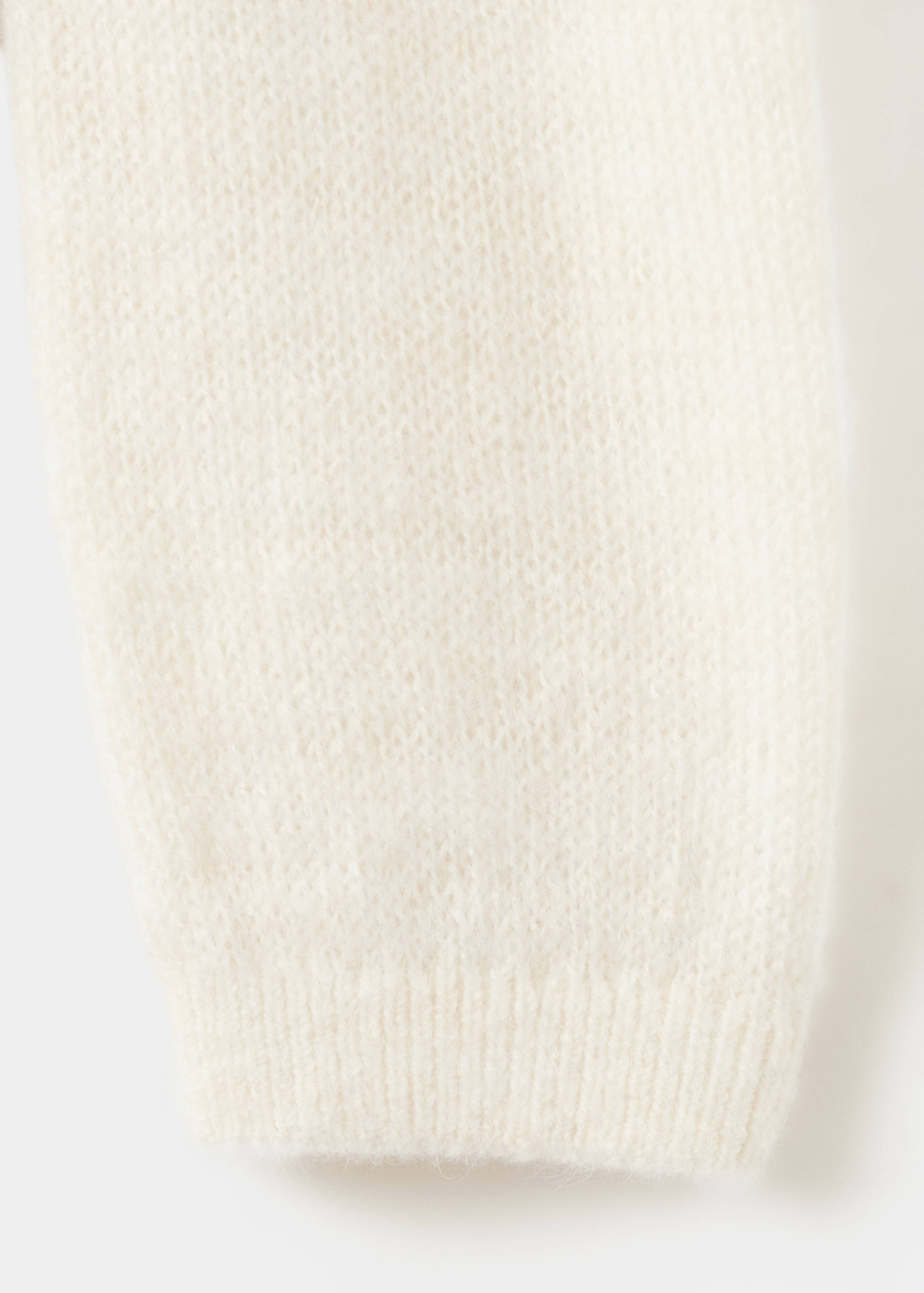 Primer plano del tejido de cárdigans en color crema que muestra una textura de punto suave.