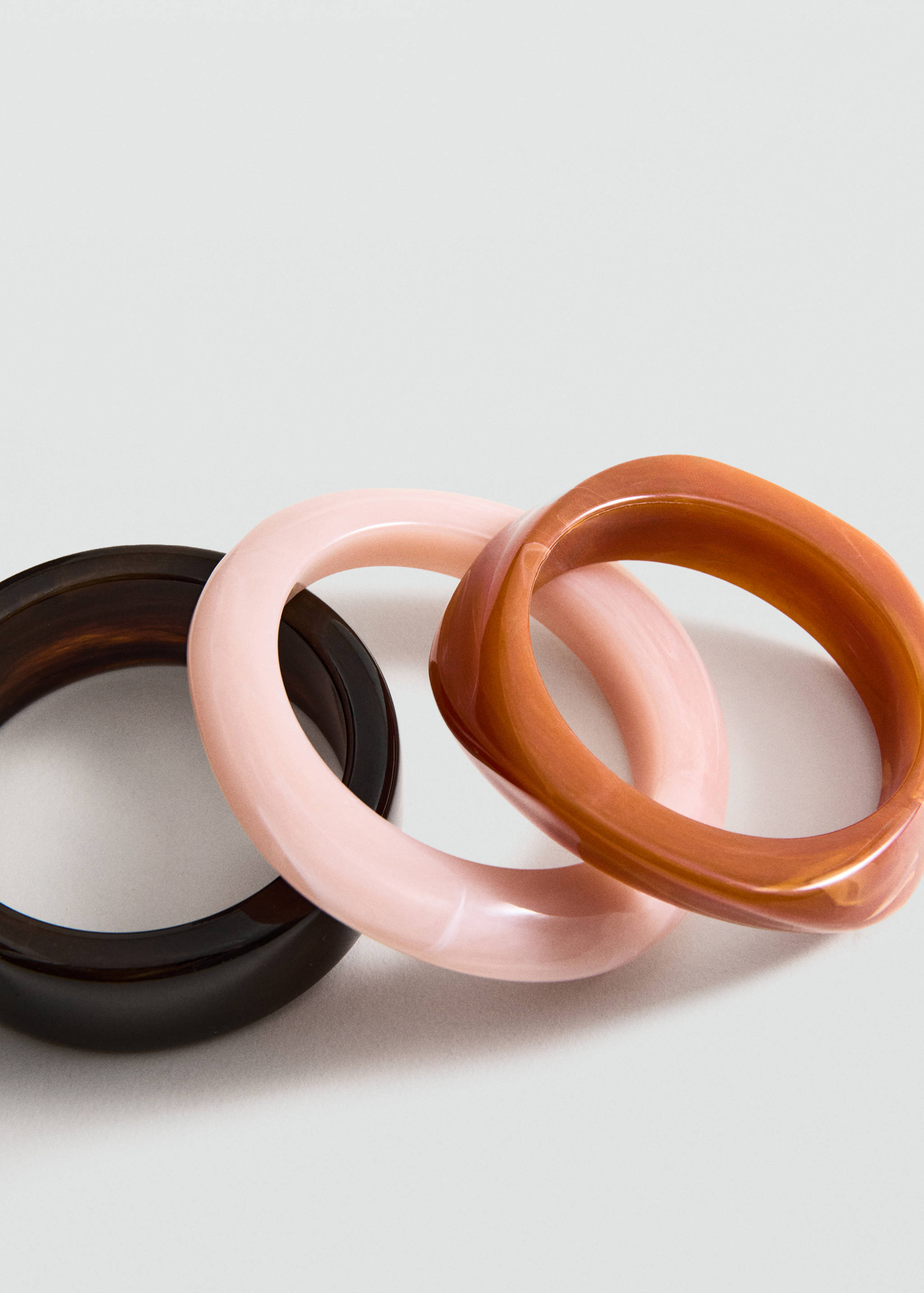 Three glossy resin bangles in dark brown, light pink, and tortoiseshell.