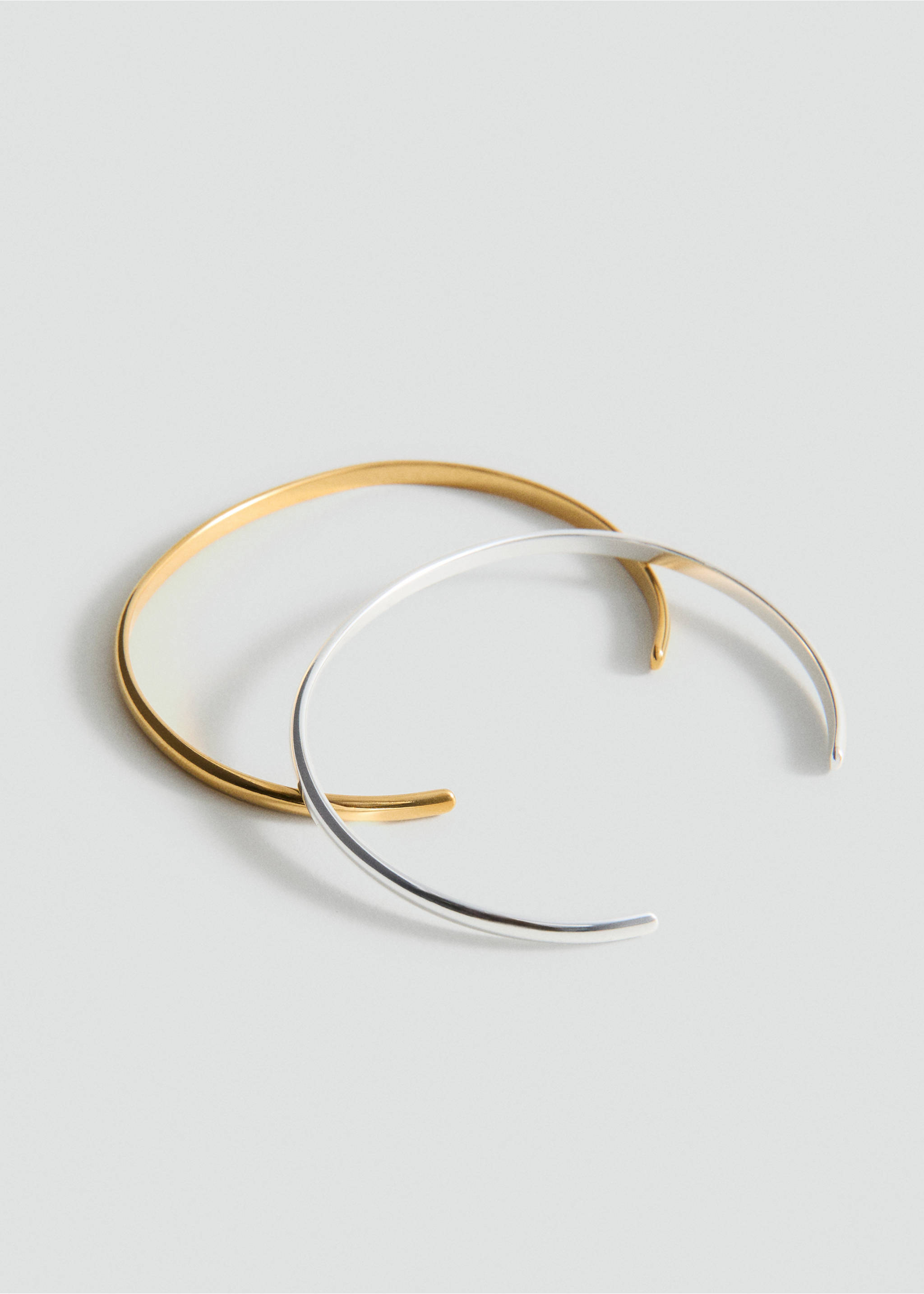Two open rigid cuff bracelets in gold and silver metal on a light grey background., Gold. Ref: 27095975-00.