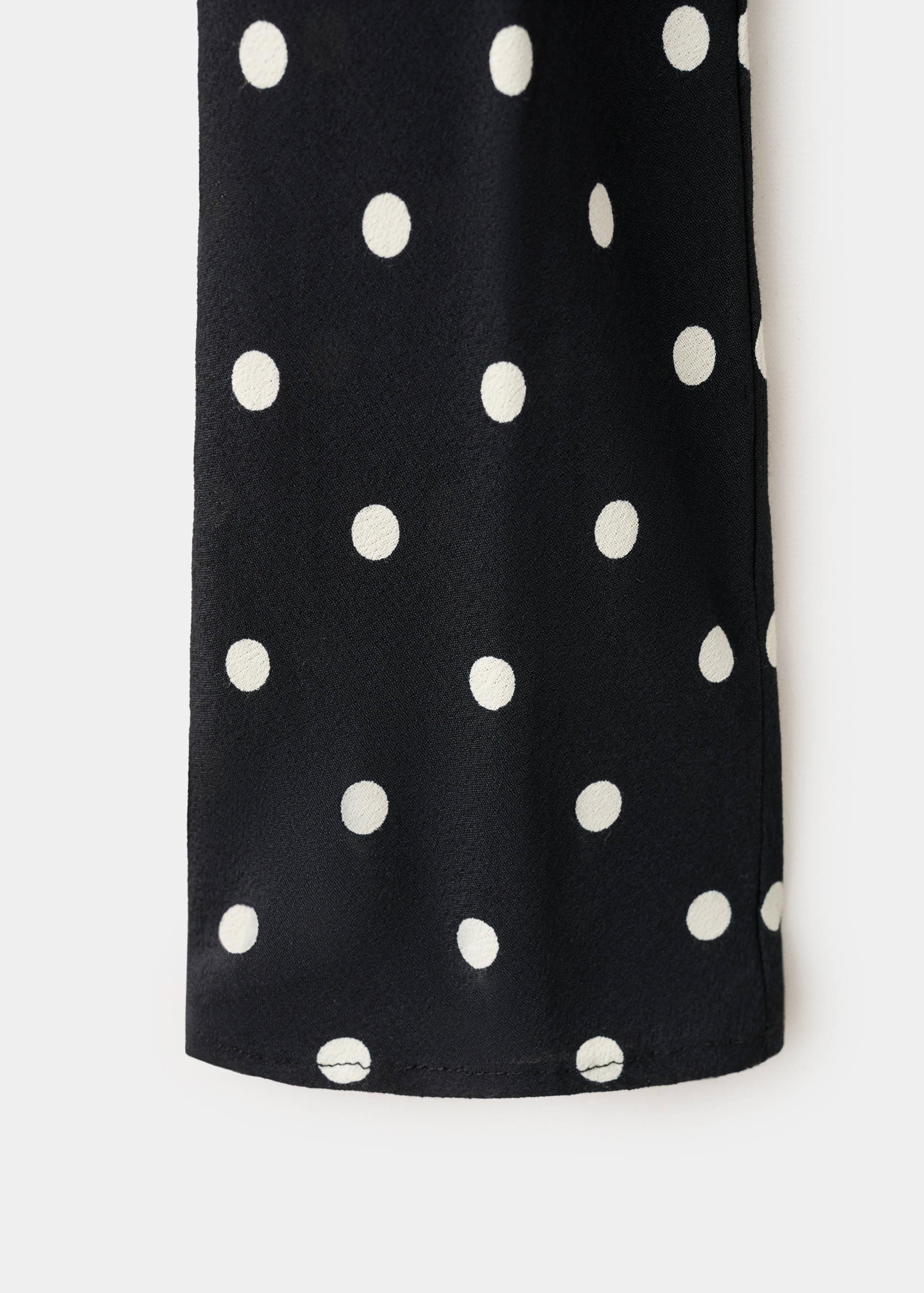 Close-up of black dress fabric with white polka dots.
