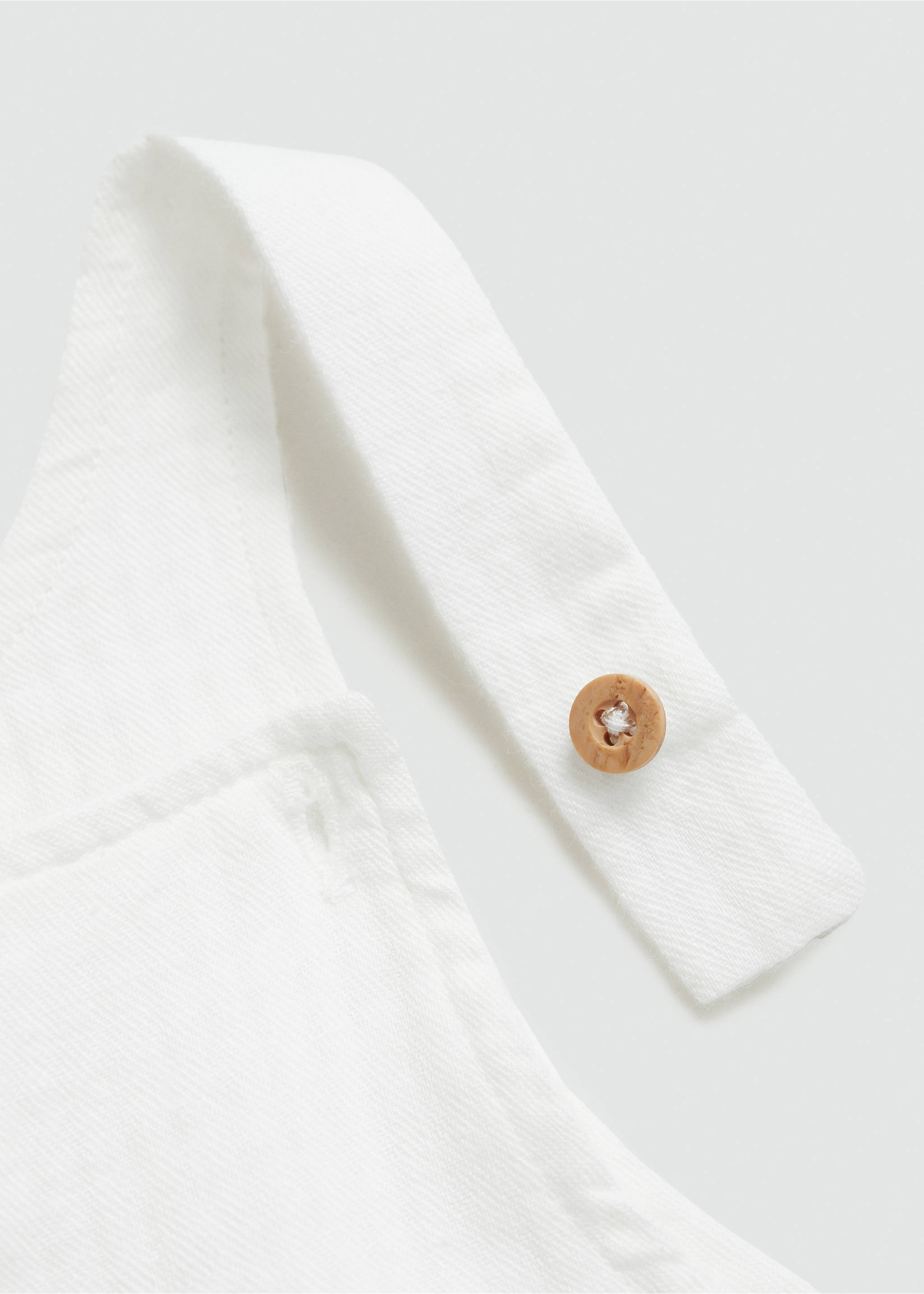 Close-up of white dungarees strap with a brown button., Off White. Ref: 77080381-00.