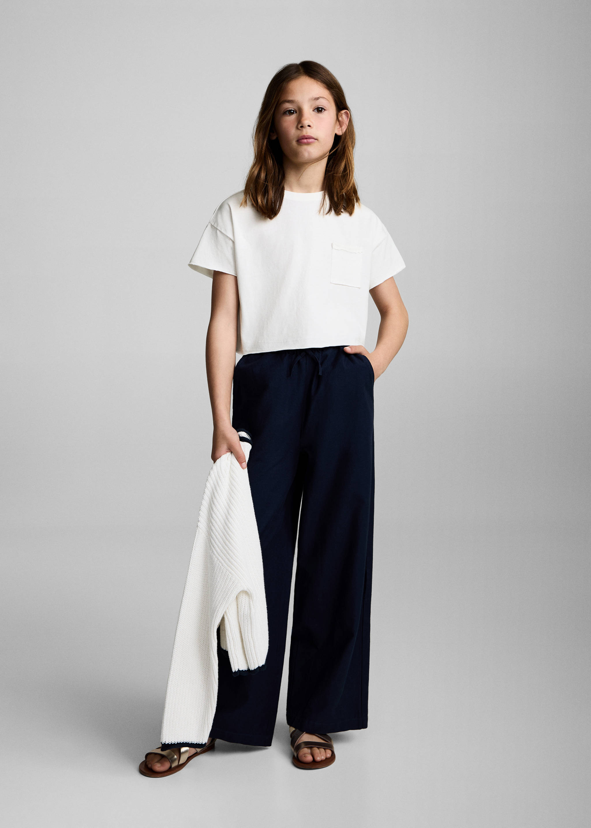 White t-shirt with a chest pocket, styled with navy blue trousers.