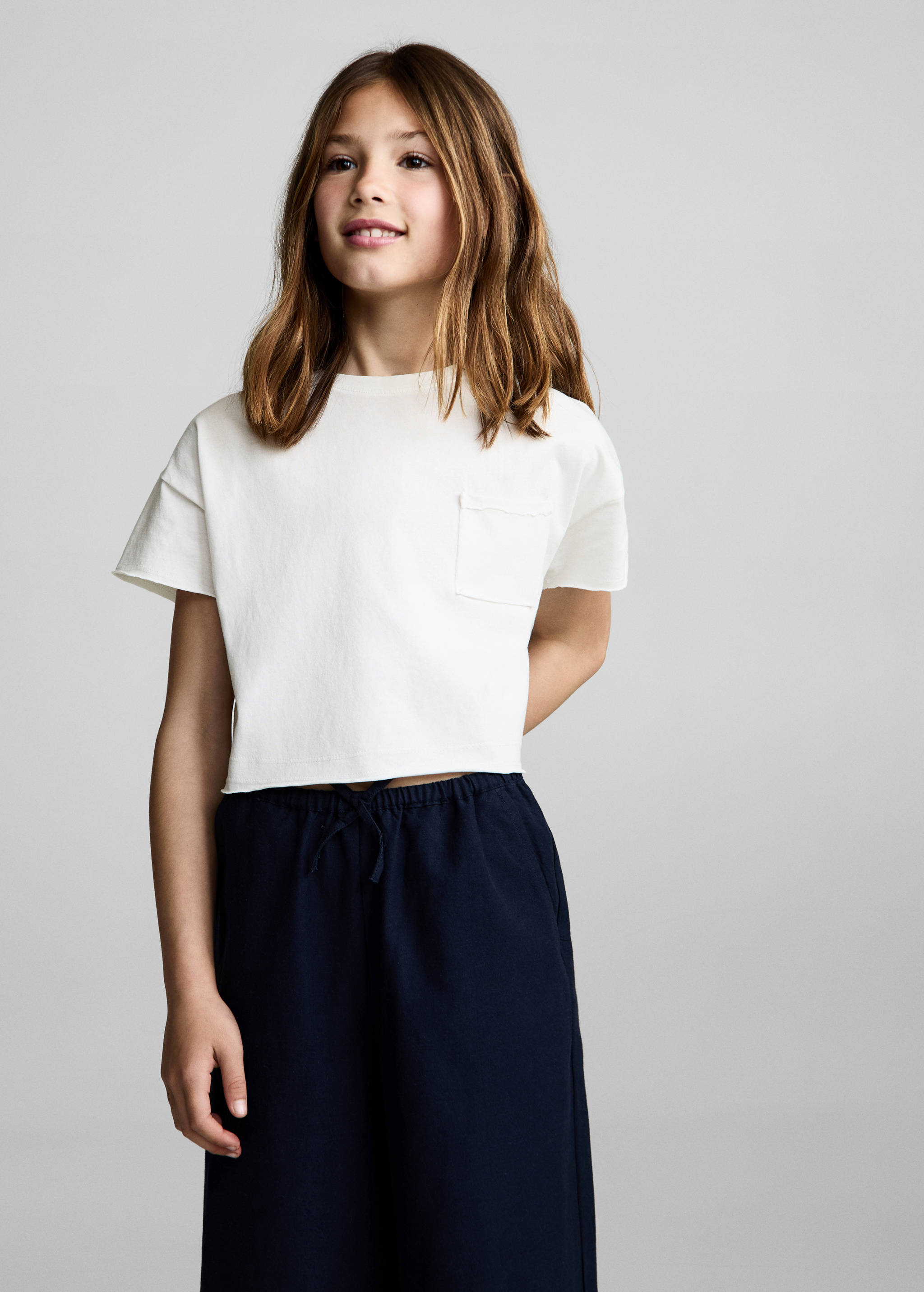 White t-shirt with short sleeves, chest pocket, and raw-edge hem.