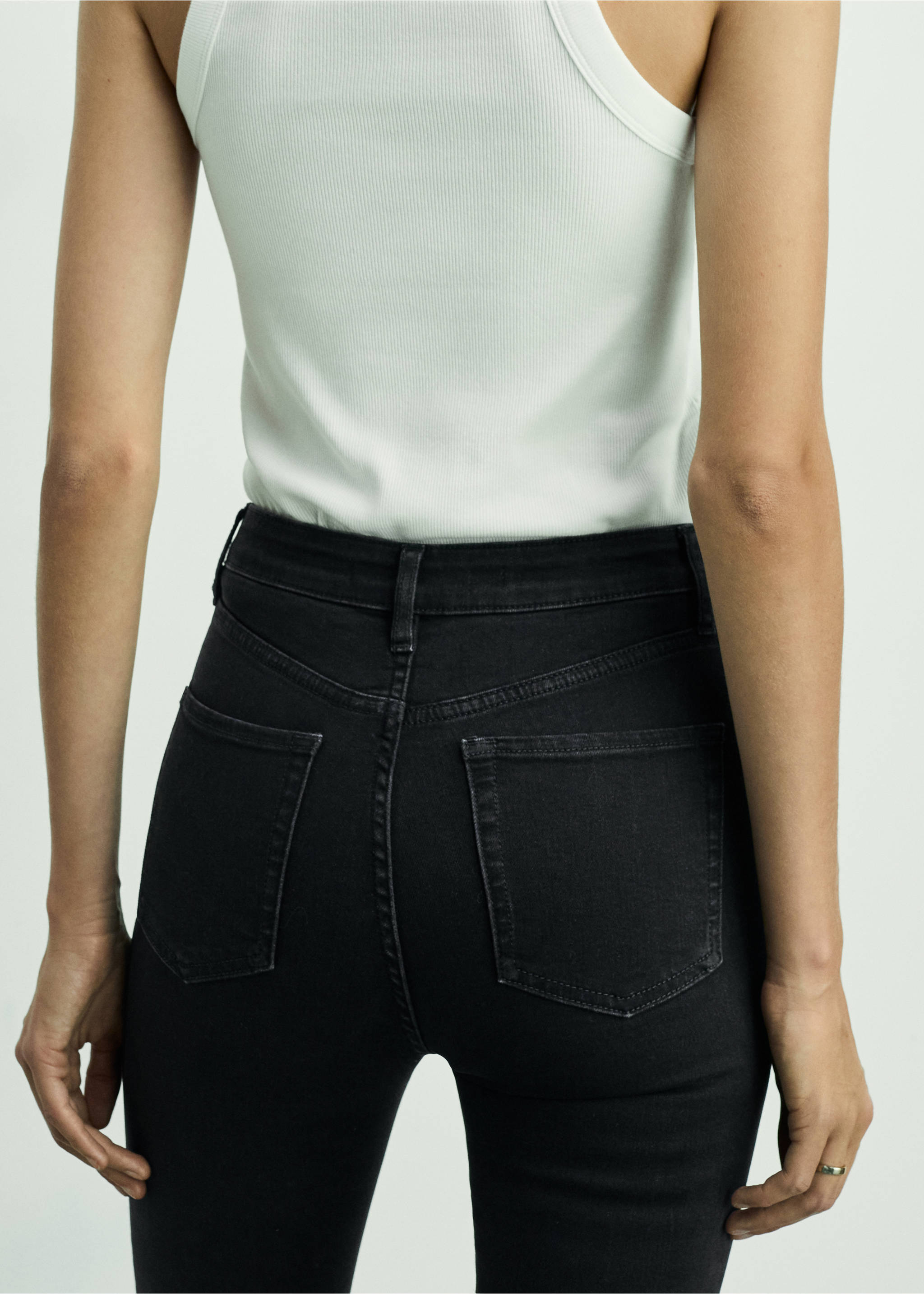 Black high-waisted skinny jeans seen from the back, worn with a white ribbed tank top., Black denim. Ref: 87010285-00.