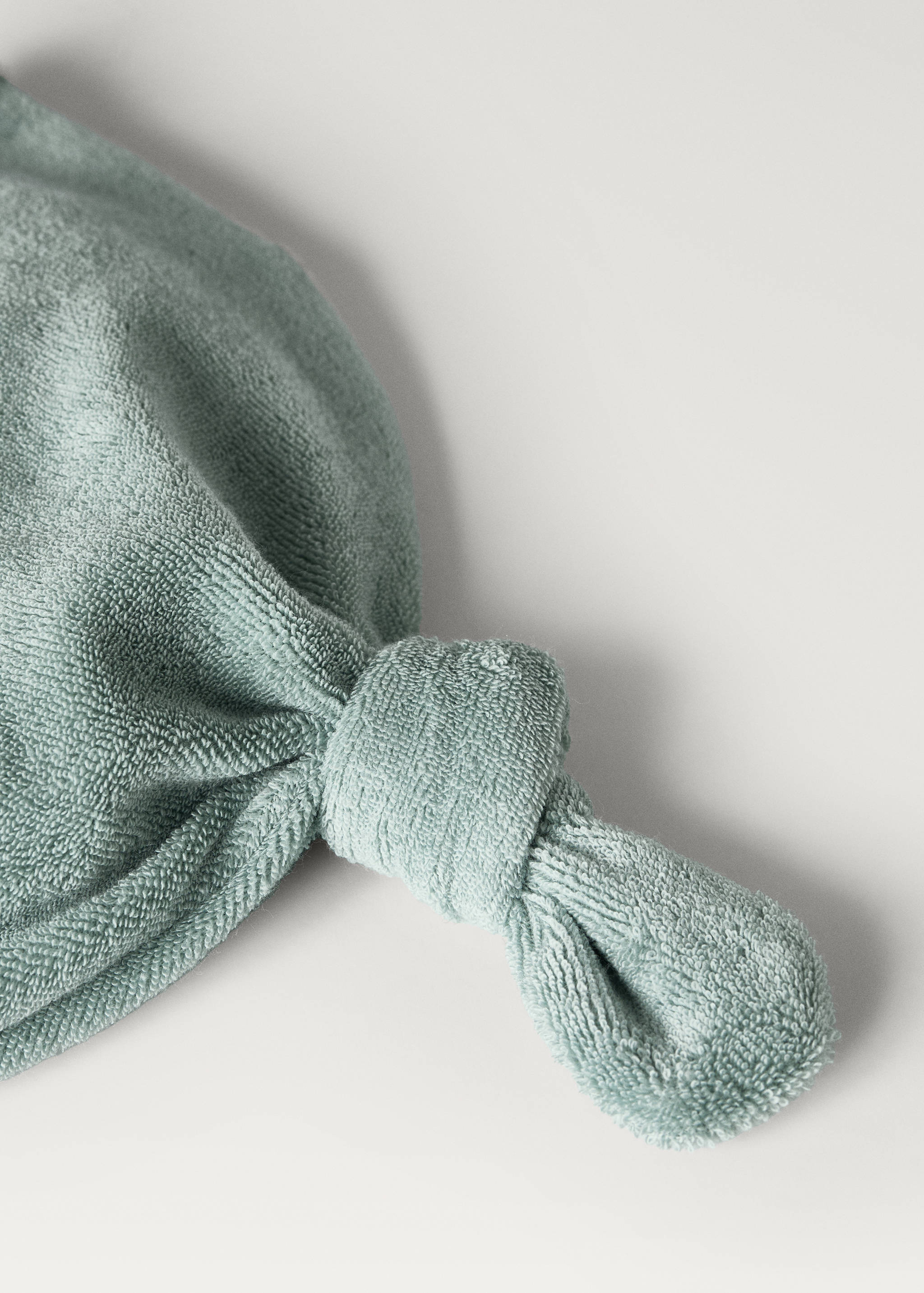 Pale green terry towel hair wrap with a knotted closure detail.