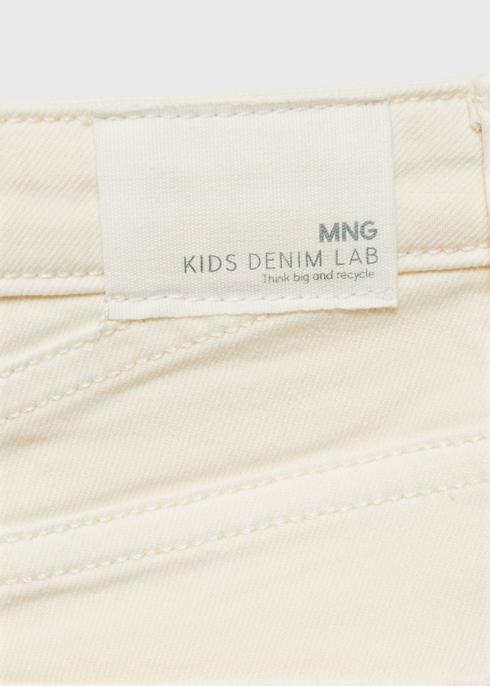 Close-up of cream kids' denim shorts featuring a branded waistband label.