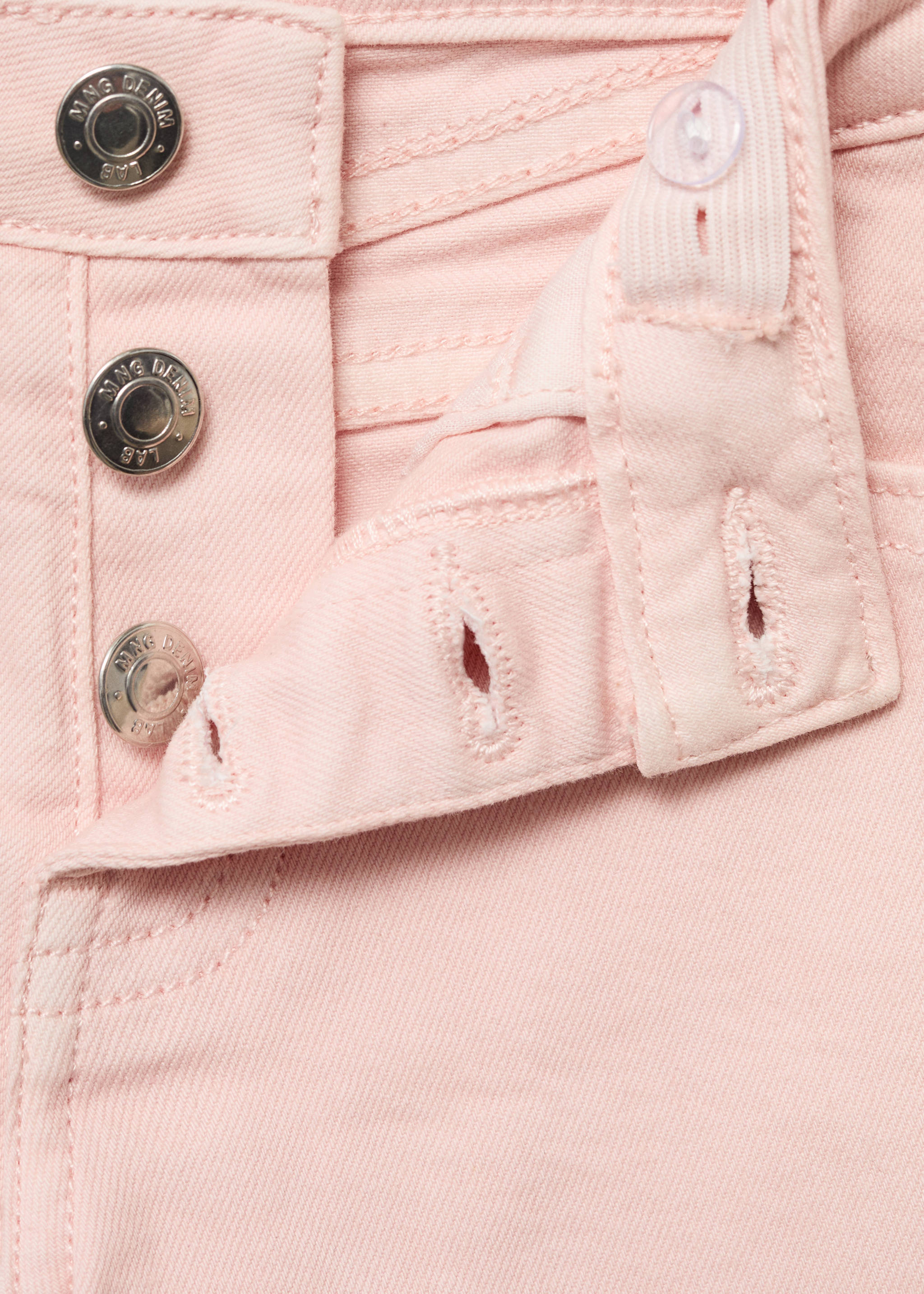 Close-up of the button fly and pink fabric on kids shorts.