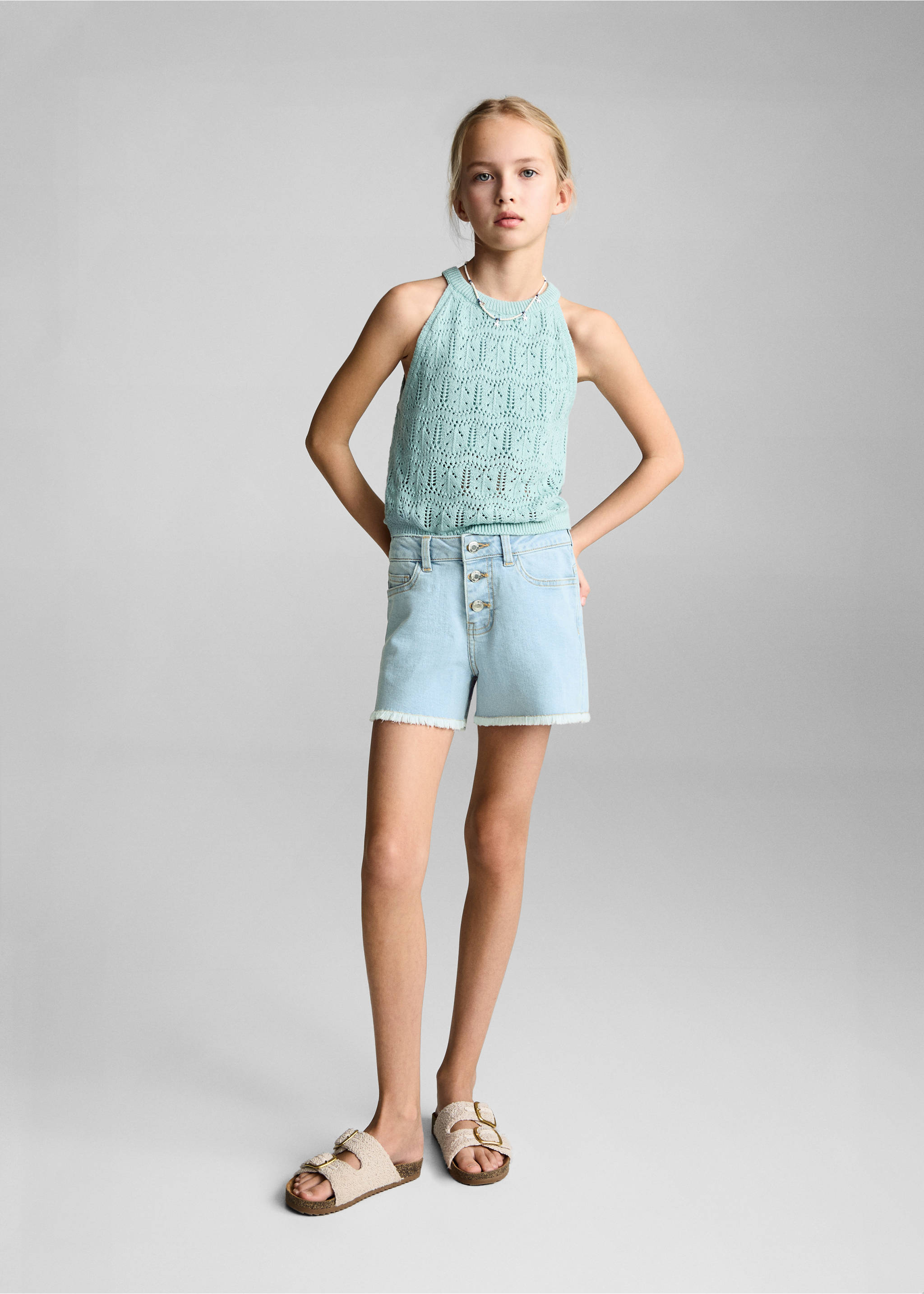 Light-blue denim shorts with a frayed hem and button fly, worn with a green halter top., Light Blue. Ref: 87025947-00.