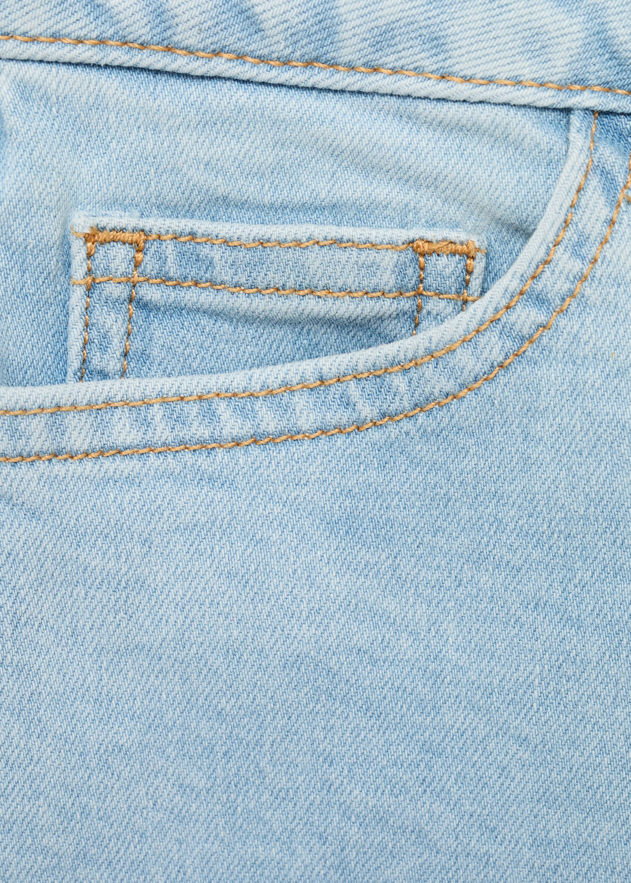 Close-up of light blue denim fabric detail on kids shorts with contrast stitching.